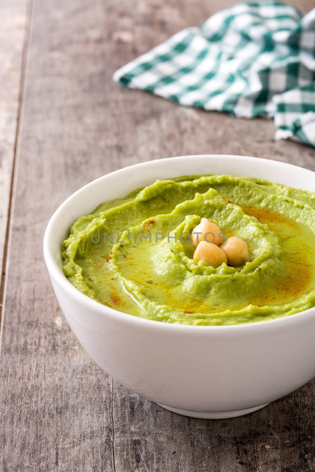 Avocado hummus in bowl on wooden table by chandlervid85