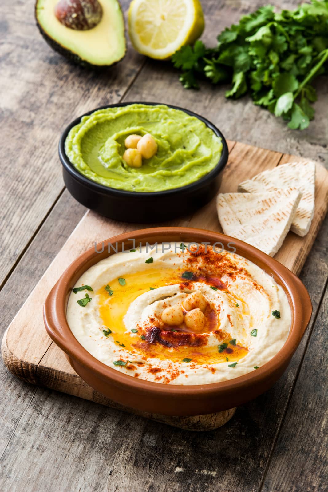 Different hummus bowls. Chickpea hummus, avocado hummus and lentils hummus on wooden table by chandlervid85