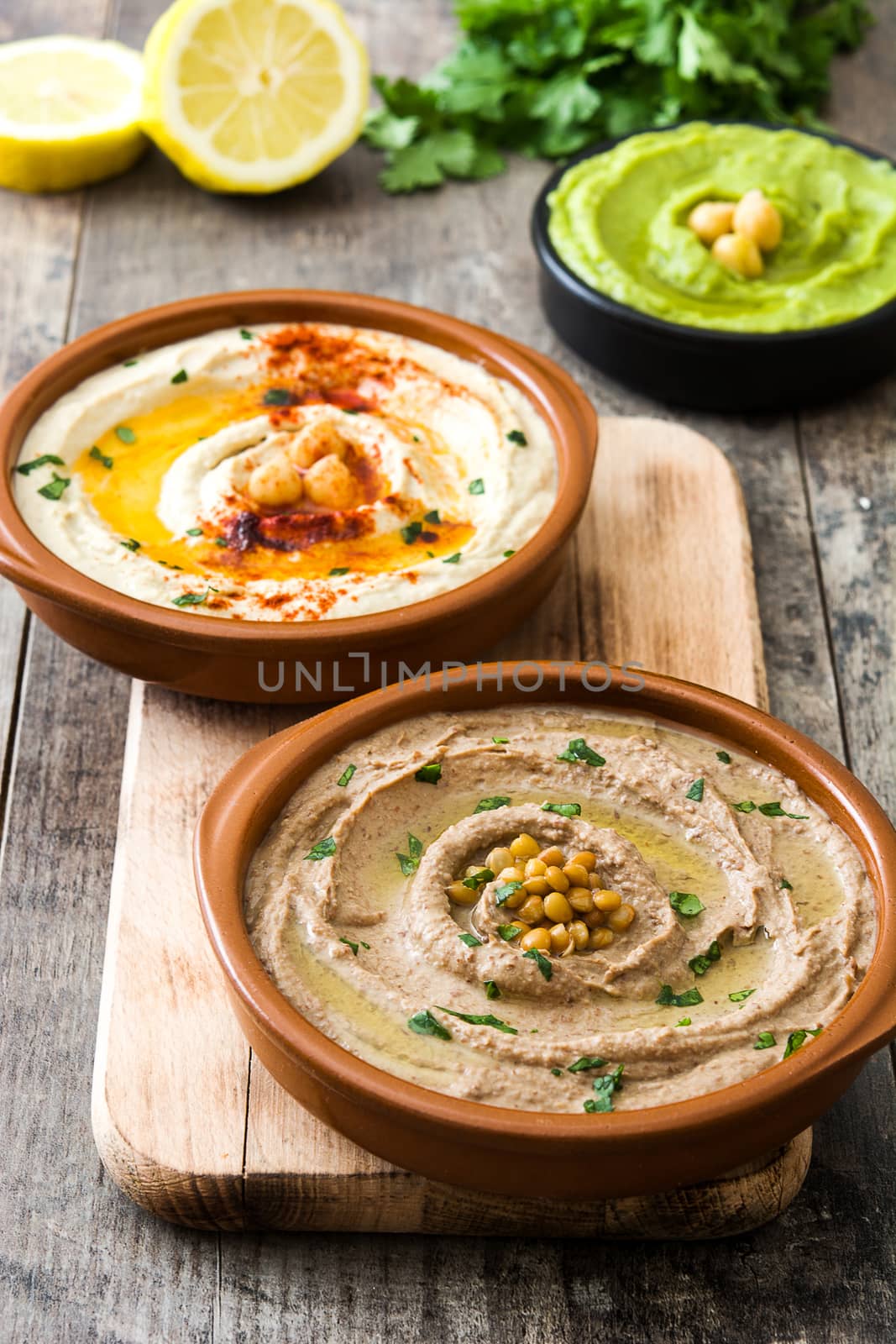 Different hummus bowls. Chickpea hummus, avocado hummus and lentils hummus on wooden table