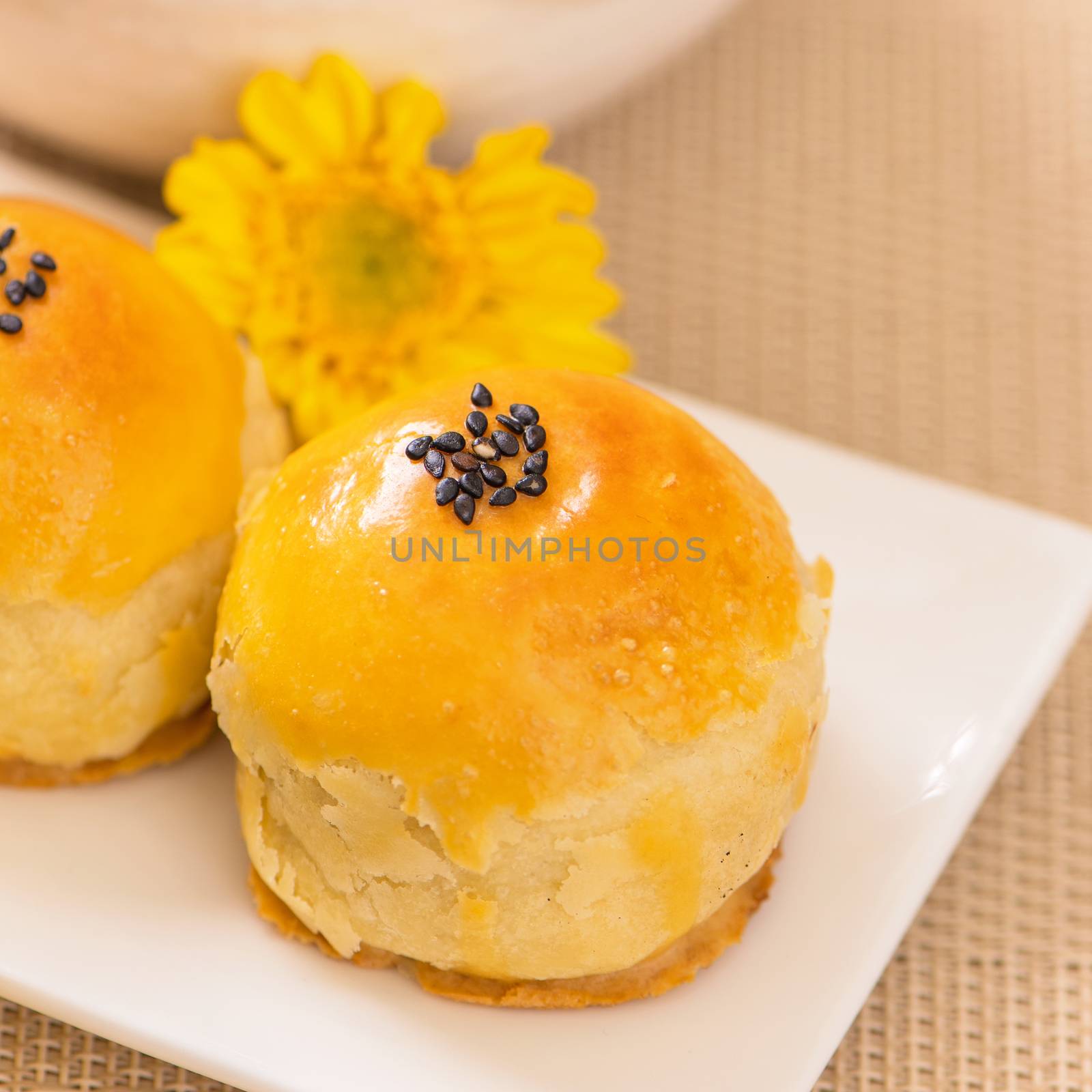 Tasty baked egg yolk pastry moon cake for Mid-Autumn Festival on bright wooden table background. Chinese festive food concept, close up, copy space.