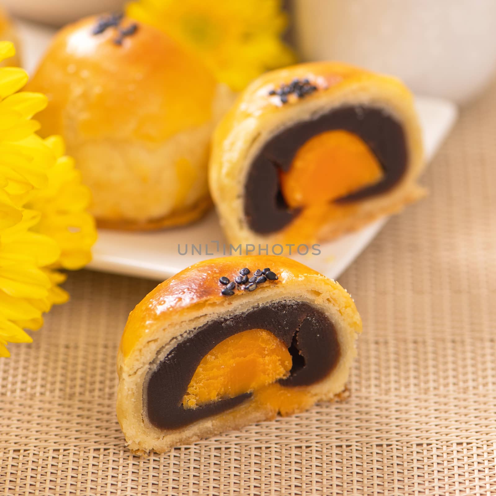 Tasty baked egg yolk pastry moon cake for Mid-Autumn Festival on bright wooden table background. Chinese festive food concept, close up, copy space.