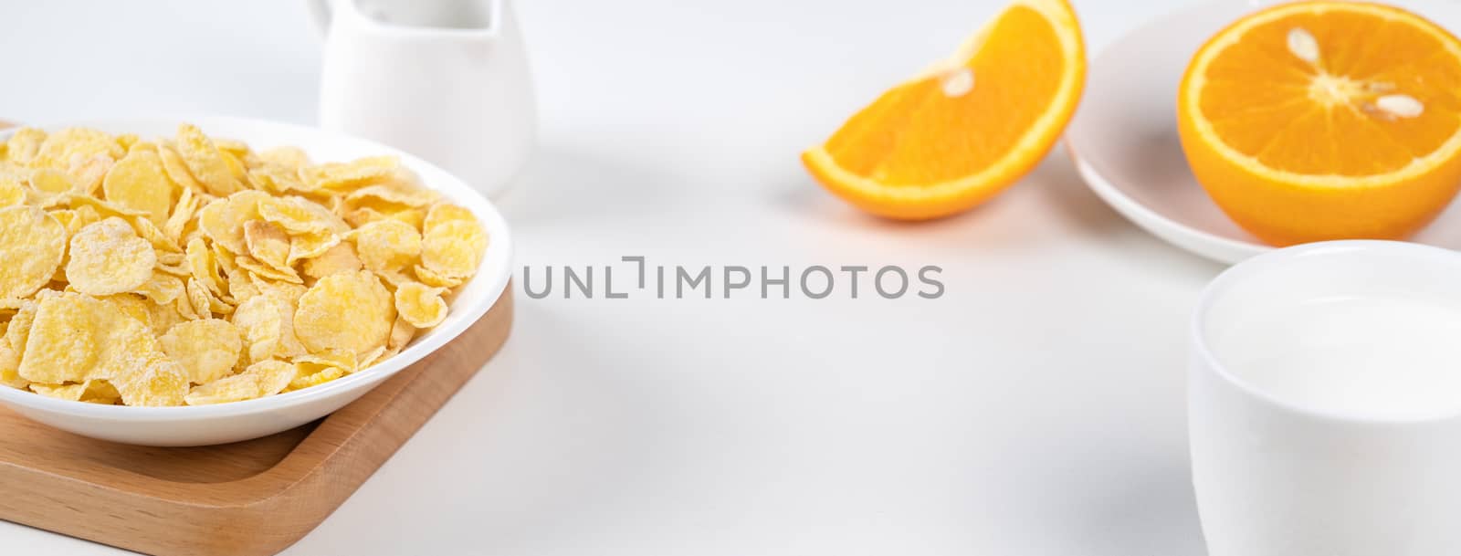 Corn flakes bowl sweeties with milk and orange on white backgrou by ROMIXIMAGE