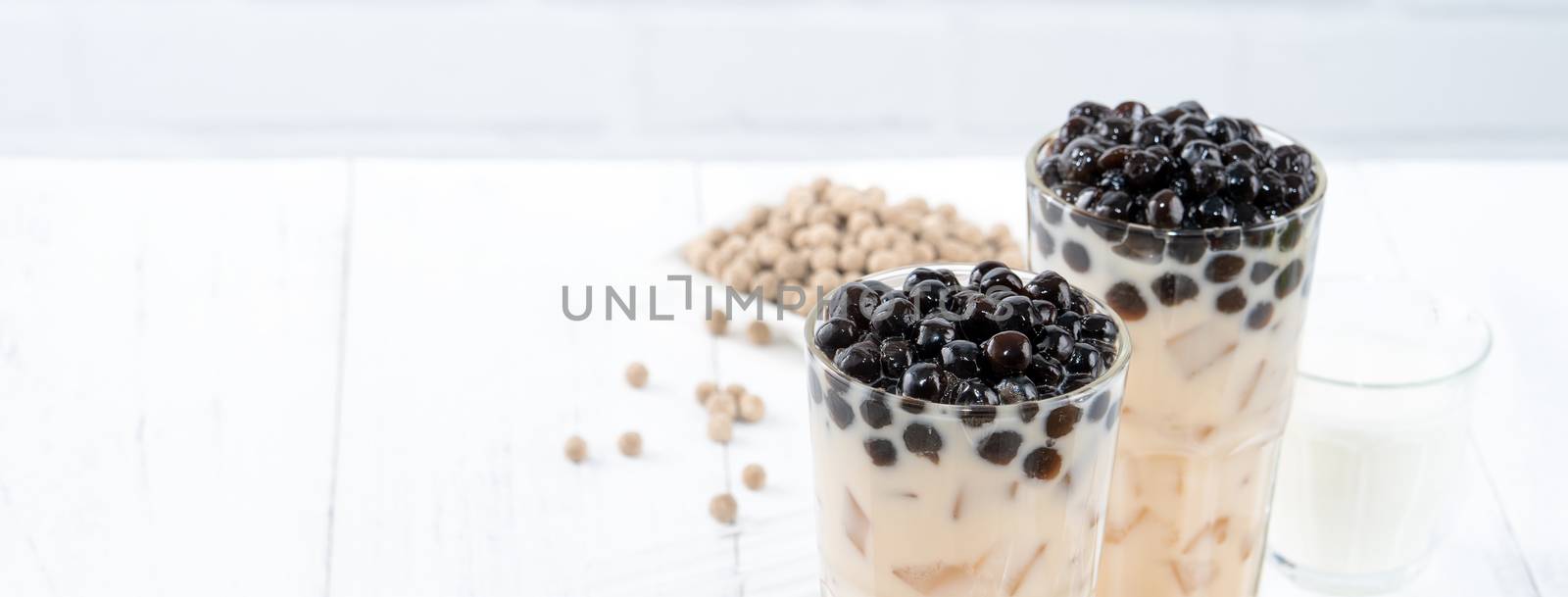 Bubble milk tea with tapioca pearl topping, famous Taiwanese drink on white wooden table background in drinking glass, close up, copy space