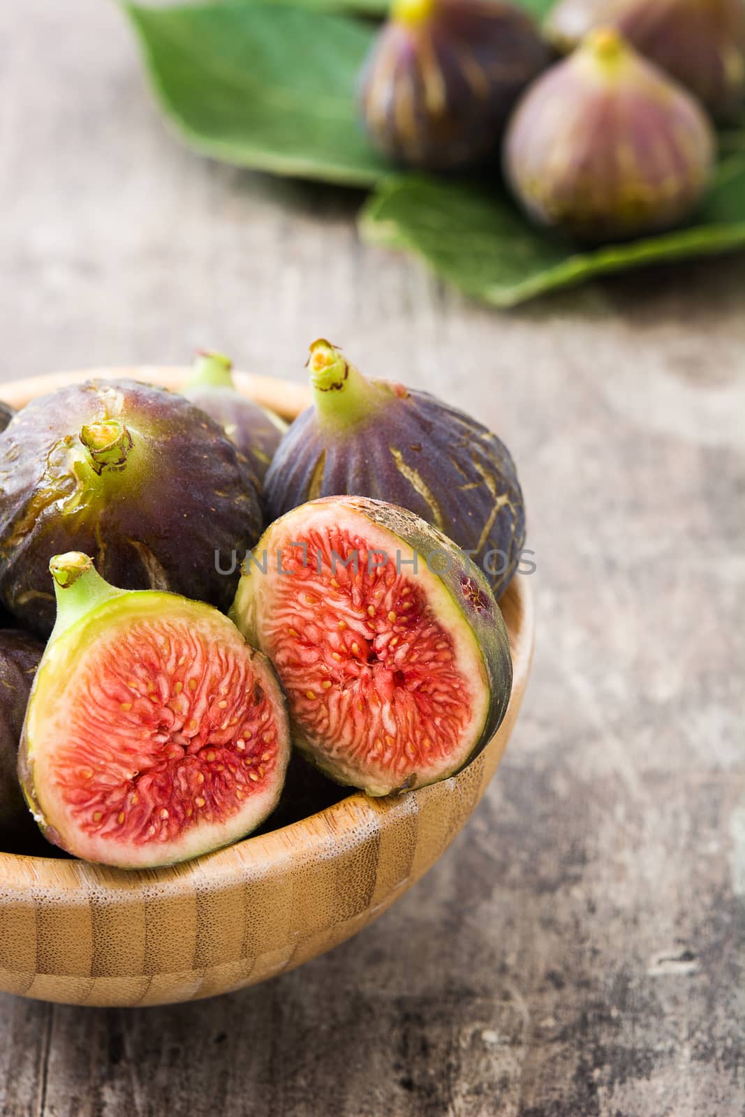 Fresh figs on wooden bowl and wooden background