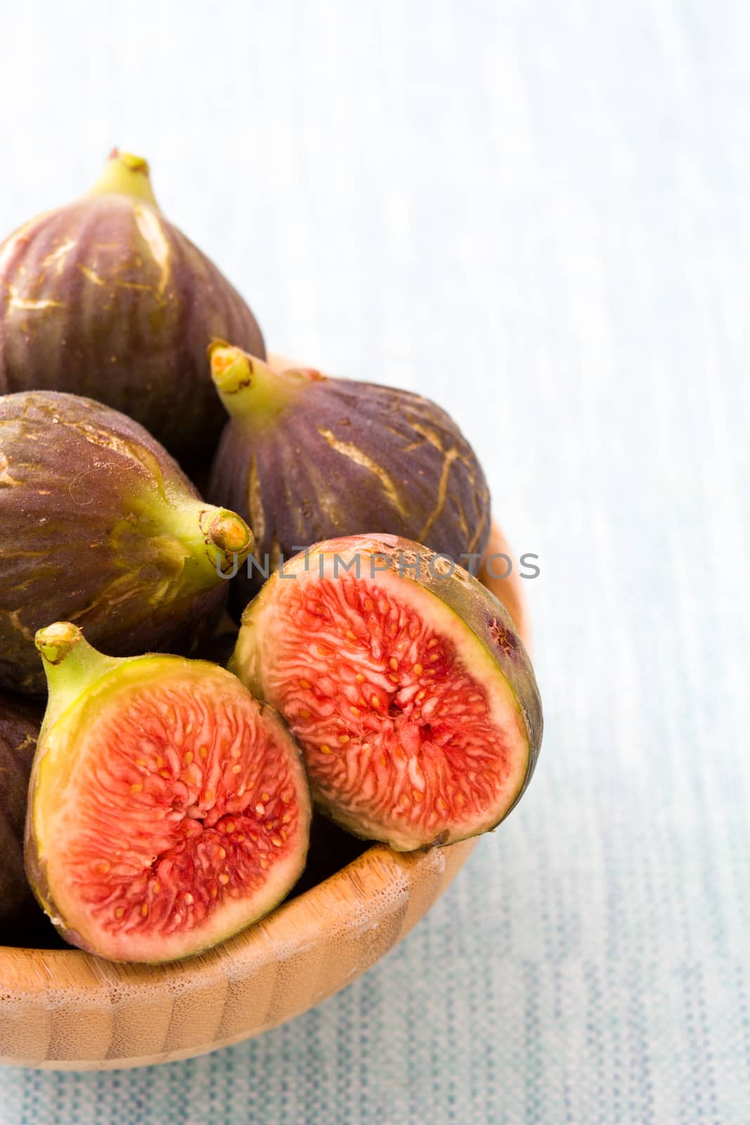 Fresh figs on wooden bowl and blue background