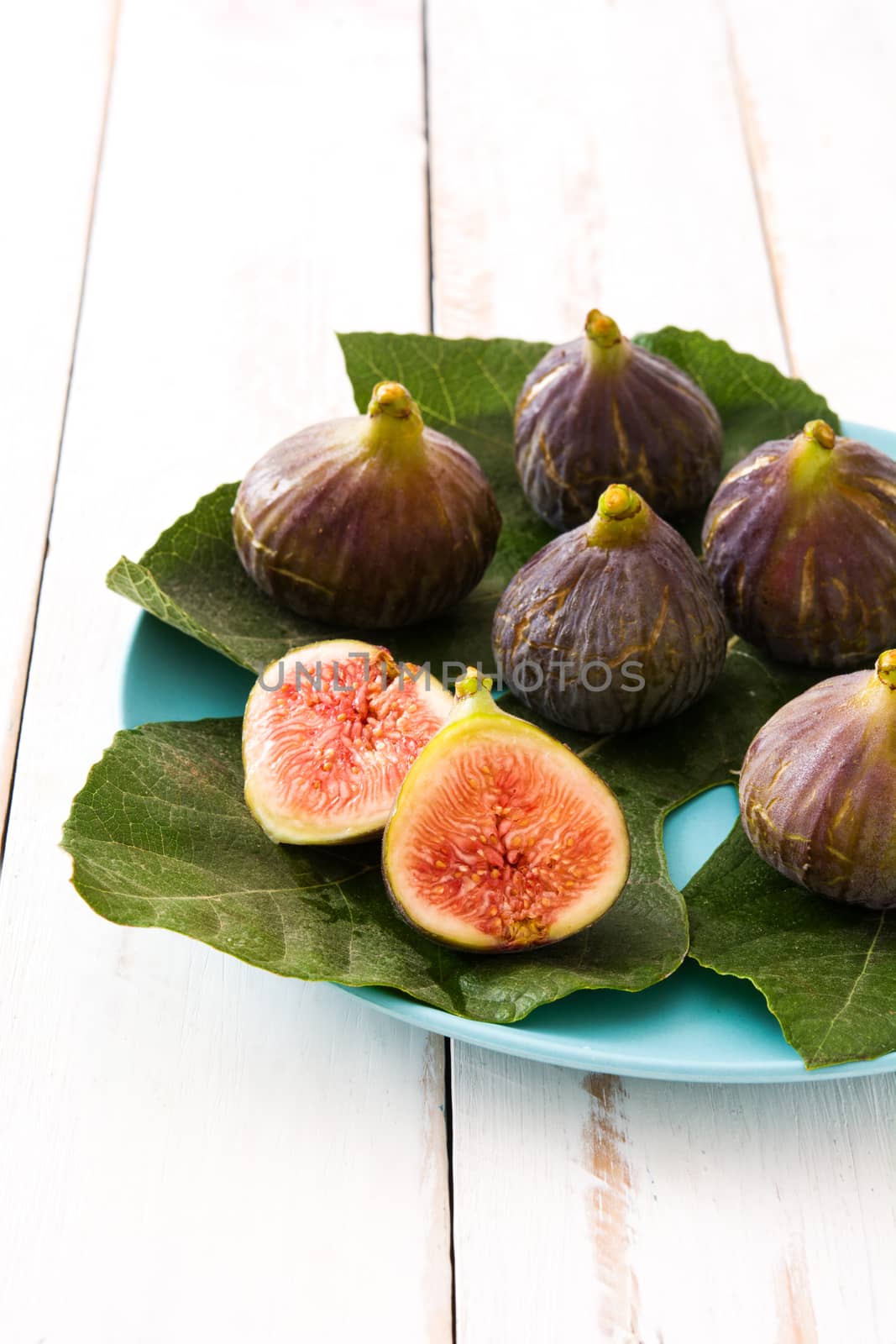 Fresh figs on white wooden background by chandlervid85