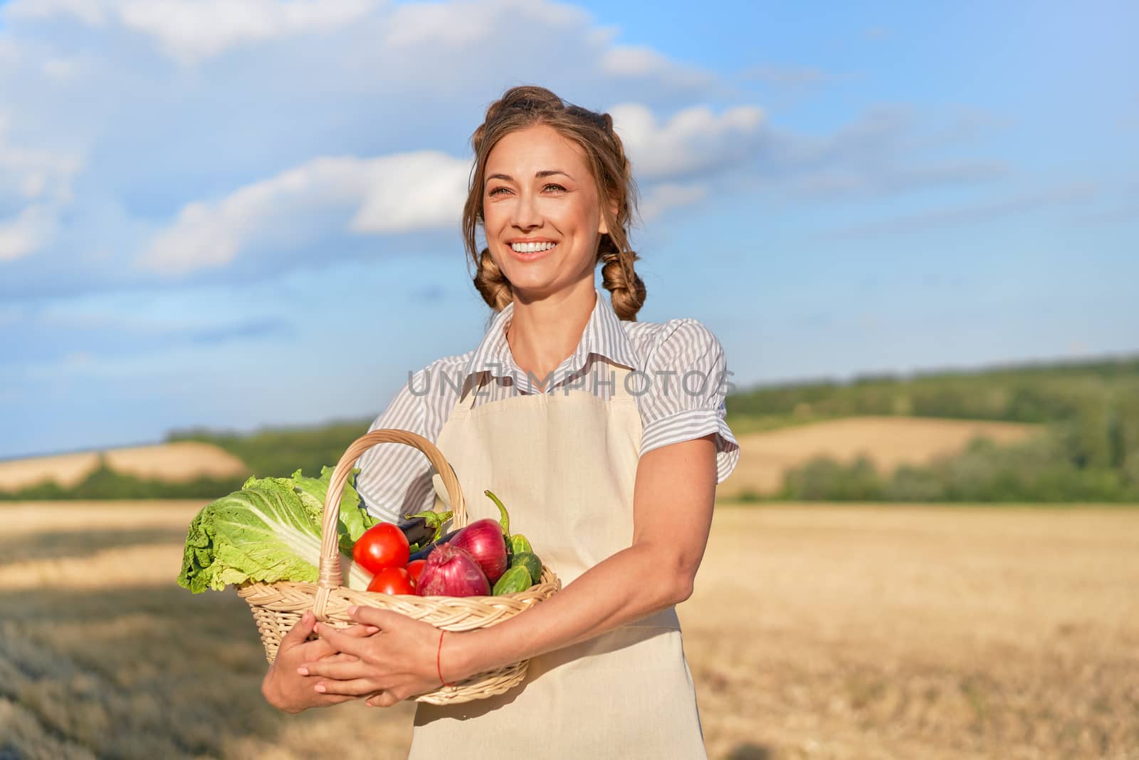 Woman farmer holding basket vegetable onion tomato salad cucumber standing farmland smiling Female agronomist specialist farming agribusiness Happy Girl dressed apron cultivated wheat field