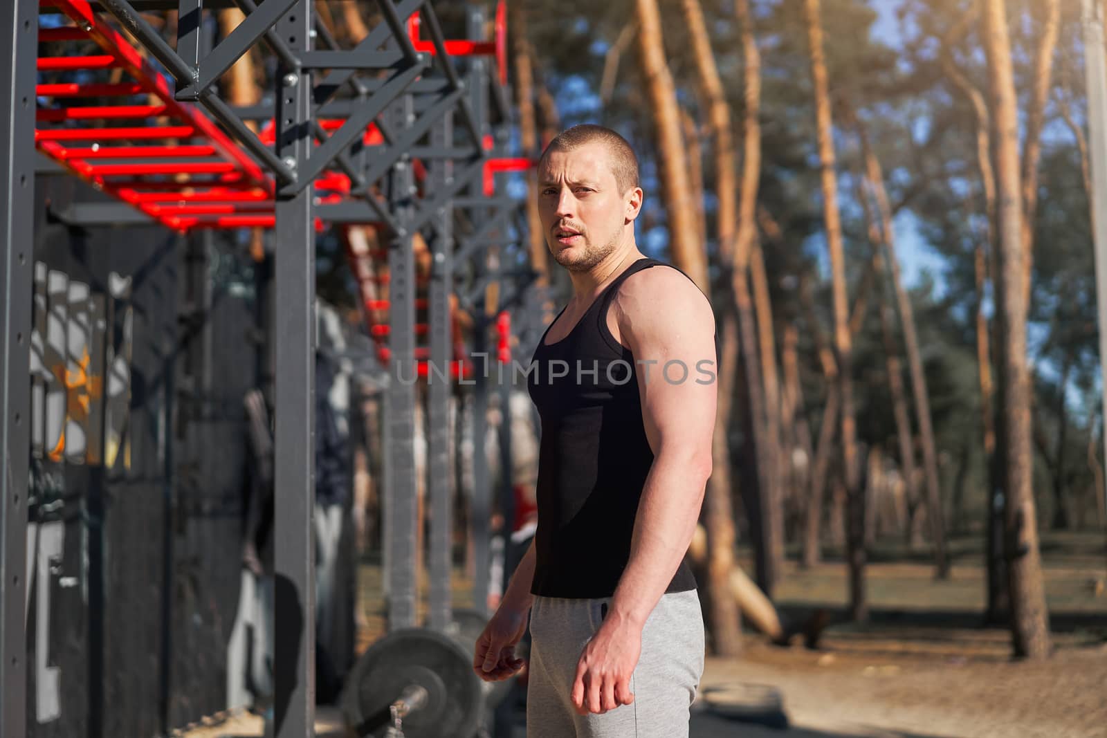 Athletic man standing outdoor gym workout. Handsome caucasian guy cross training nature public gym. Sportive people healthy lifestyle concept.