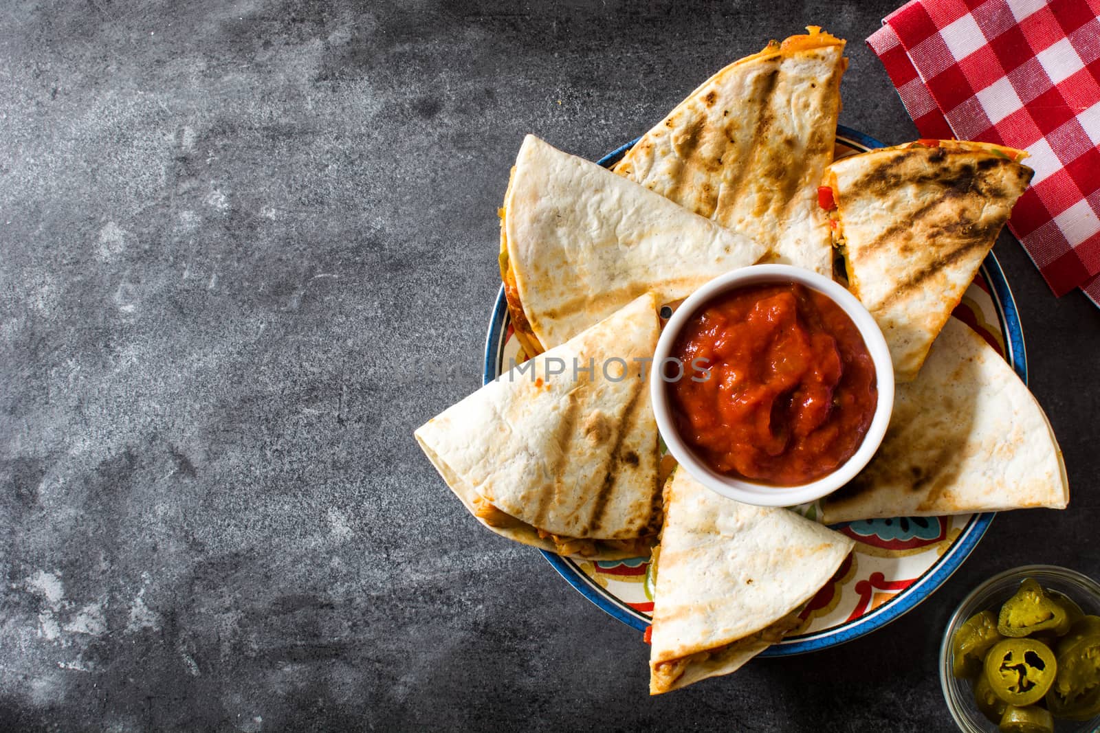 Mexican quesadilla with chicken, cheese and peppers on black background