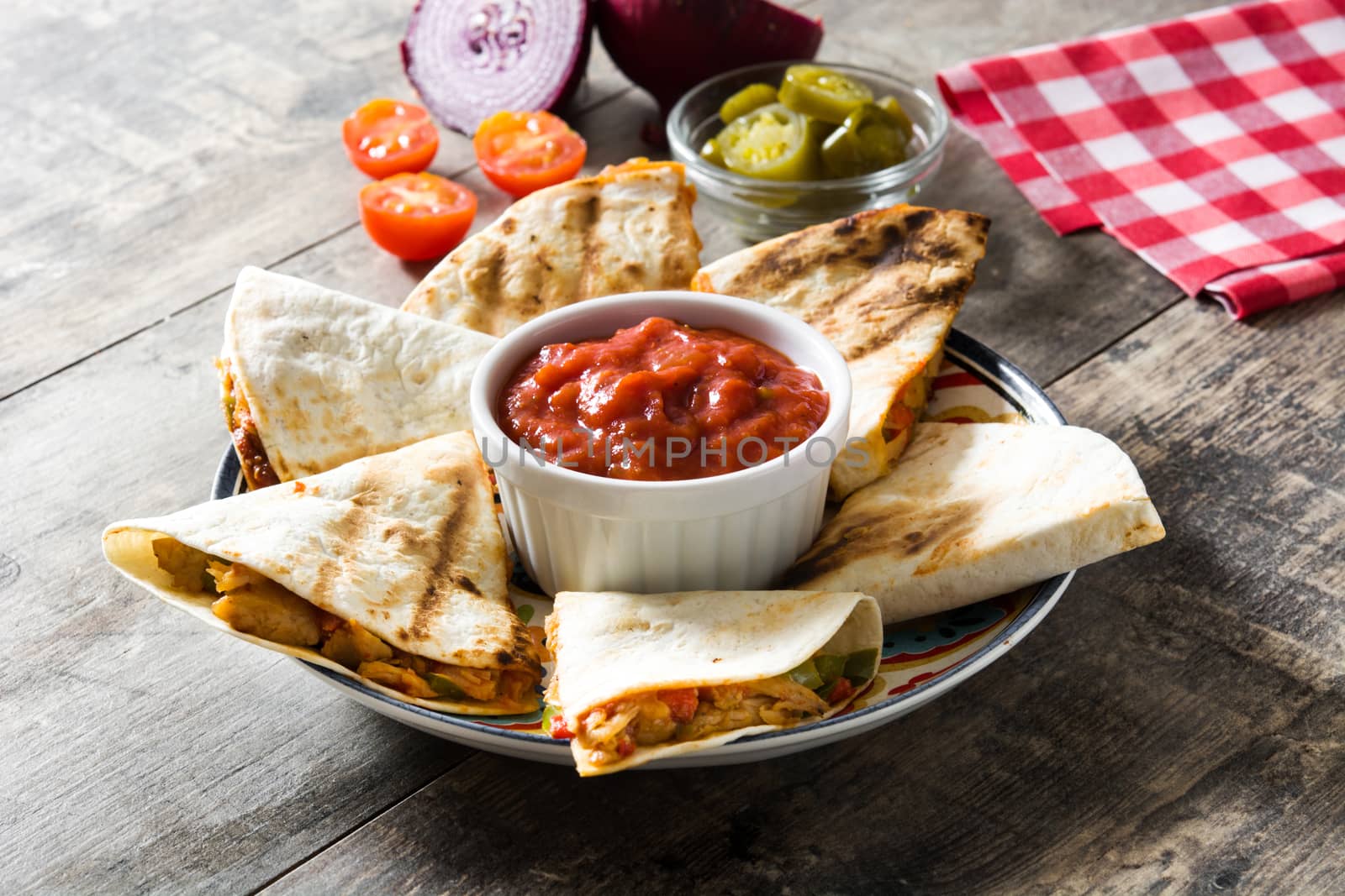 Mexican quesadilla with chicken, cheese and peppers on wooden table.