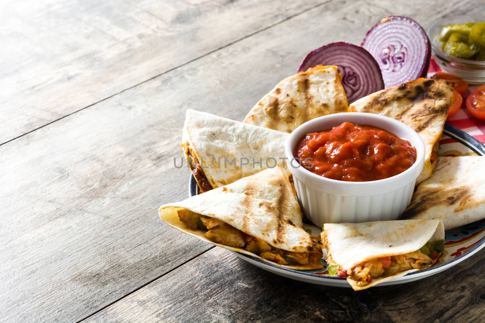 Mexican quesadilla with chicken, cheese and peppers on wooden table.