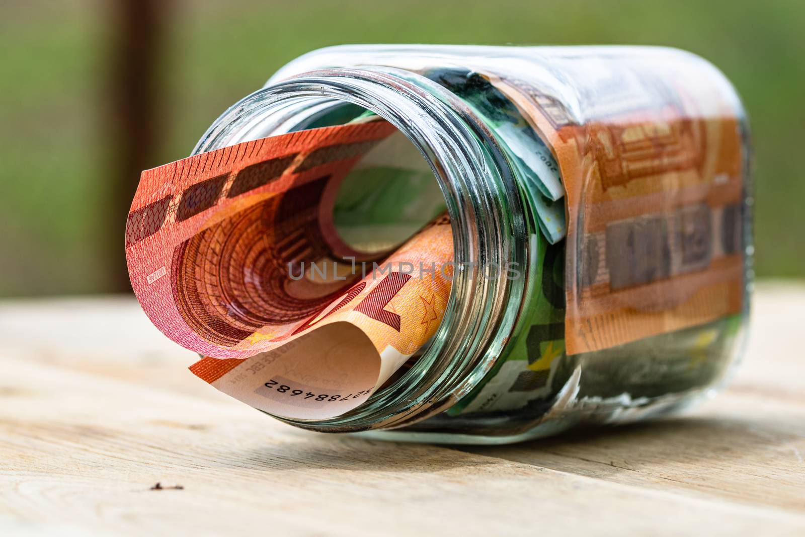 Composition with saving money banknotes in a glass jar. Concept of investing and keeping money, close up isolated.