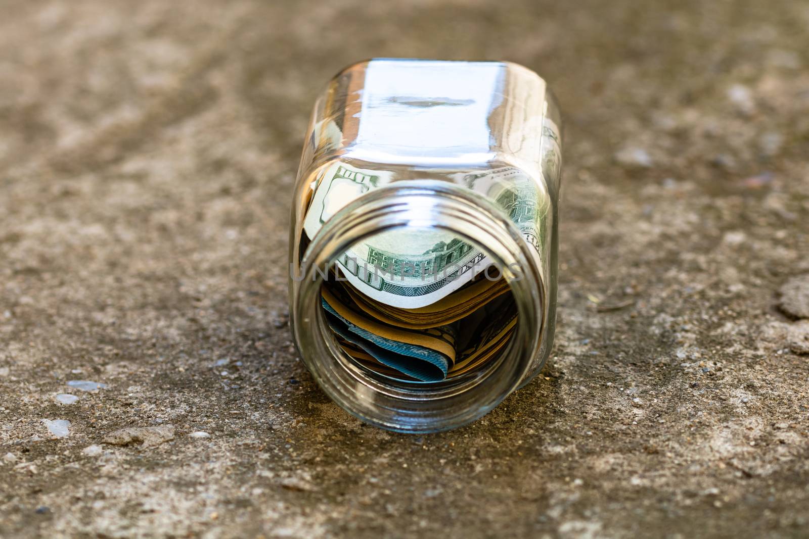 Composition with saving money banknotes in a glass jar. Concept of investing and keeping money, close up isolated.