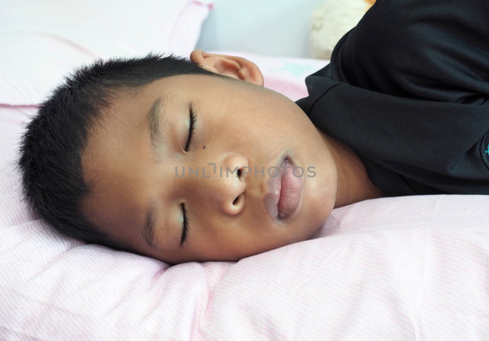 A close up of a boy sleeping on the bed by Unimages2527