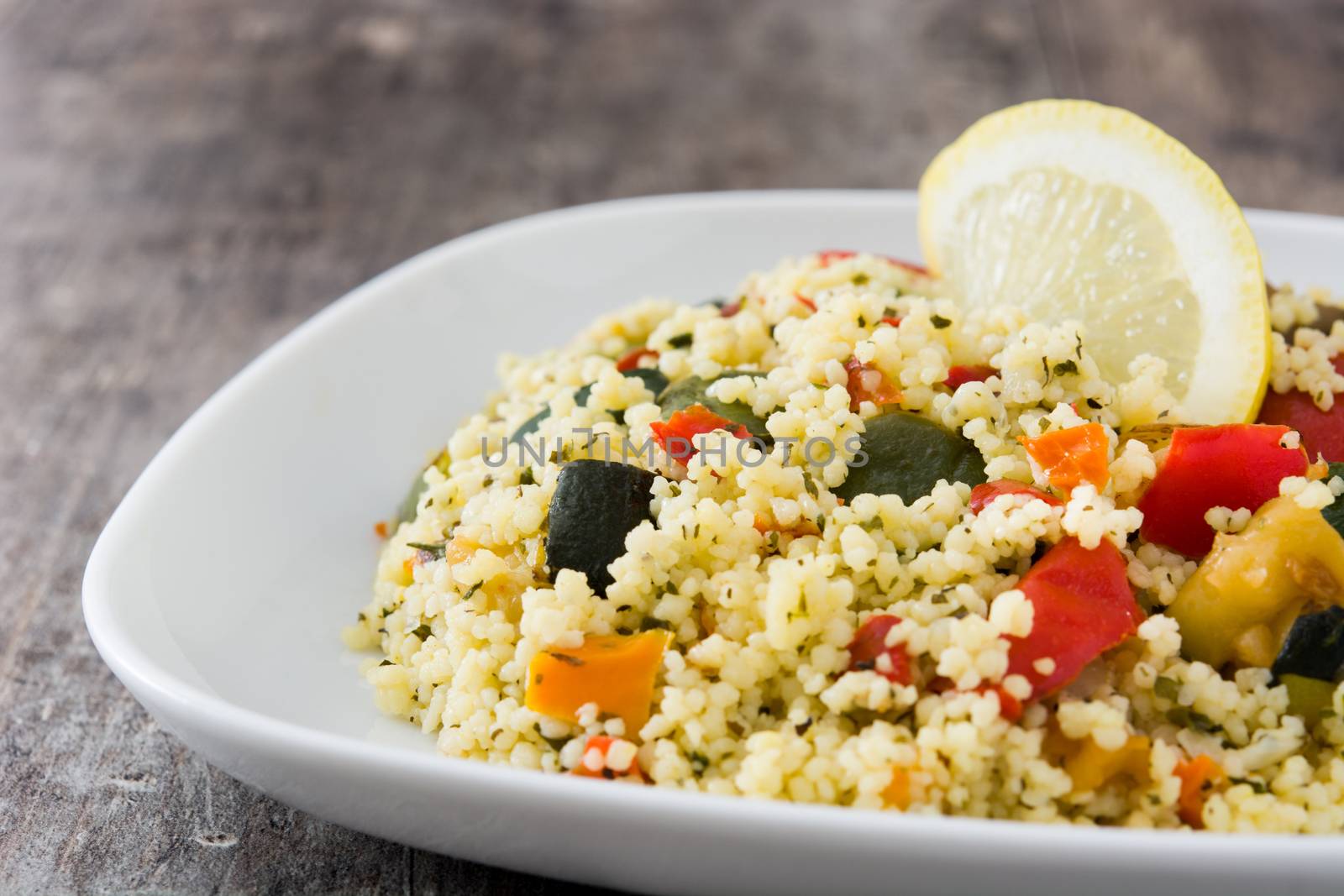 Couscous with vegetables on wooden table