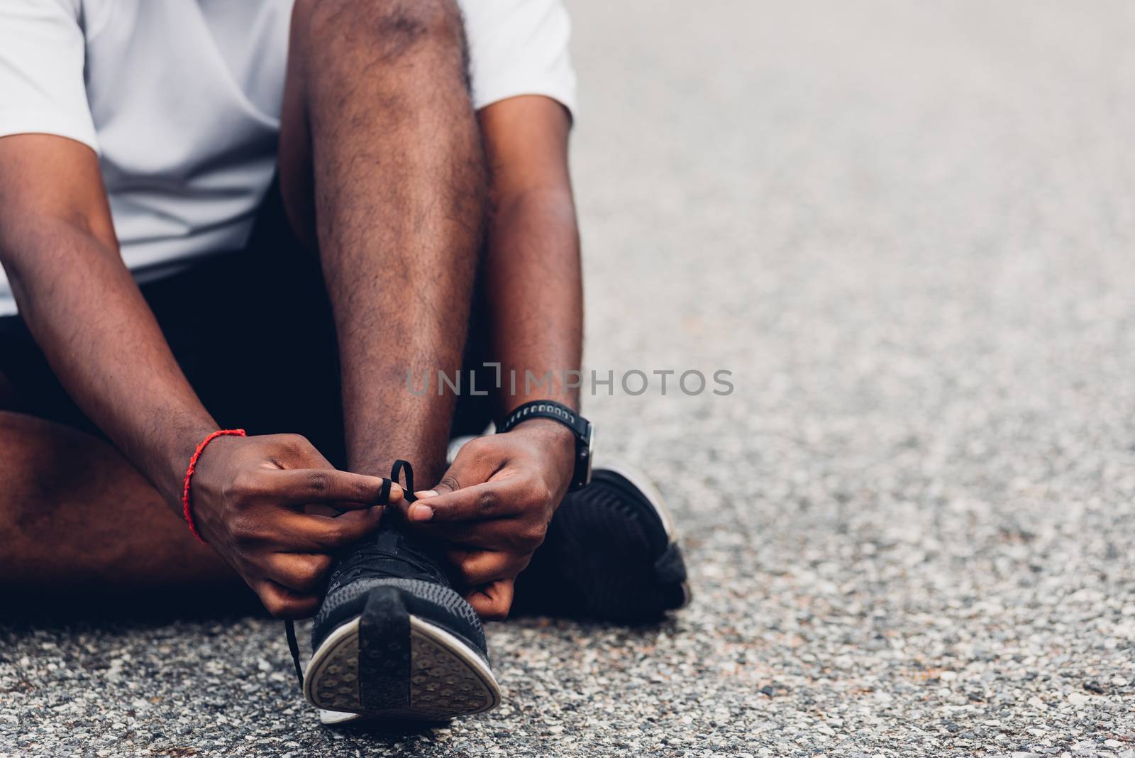 Close up Asian sport runner black man sitting shoelace trying running shoes getting ready for jogging and run at the outdoor street, health exercise workout concept