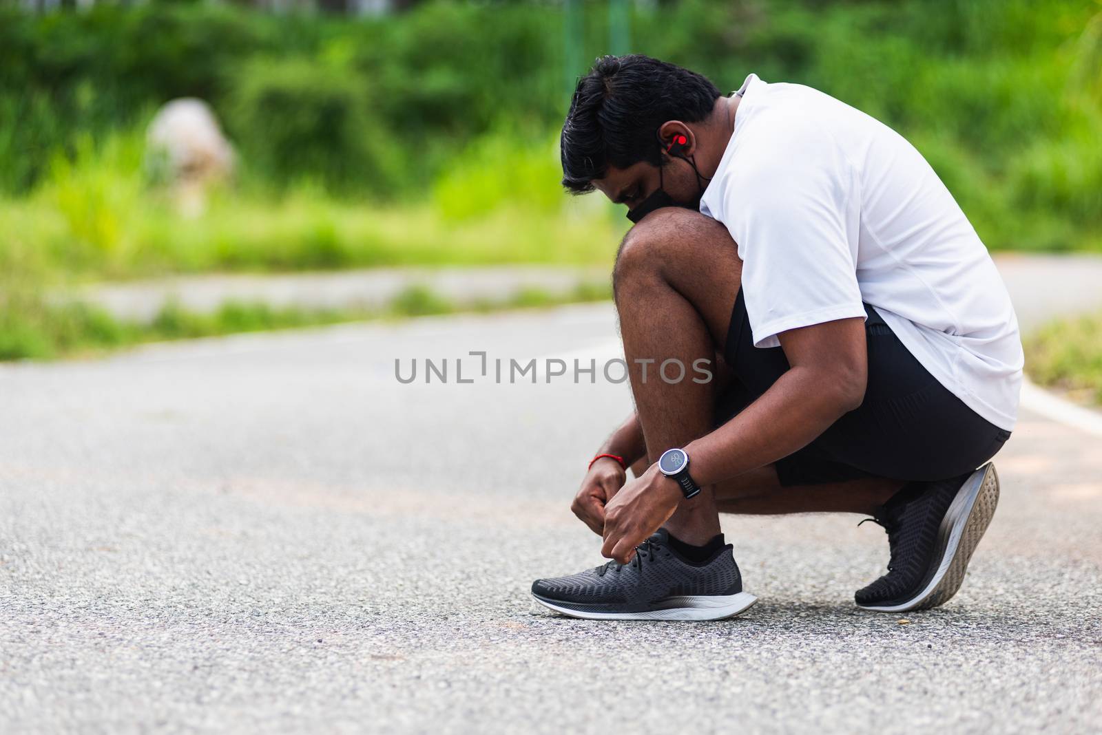 Close up Asian sport runner black man wear watch sitting he trying shoelace running shoes getting ready for jogging and run at the outdoor street health park, healthy exercise workout concept
