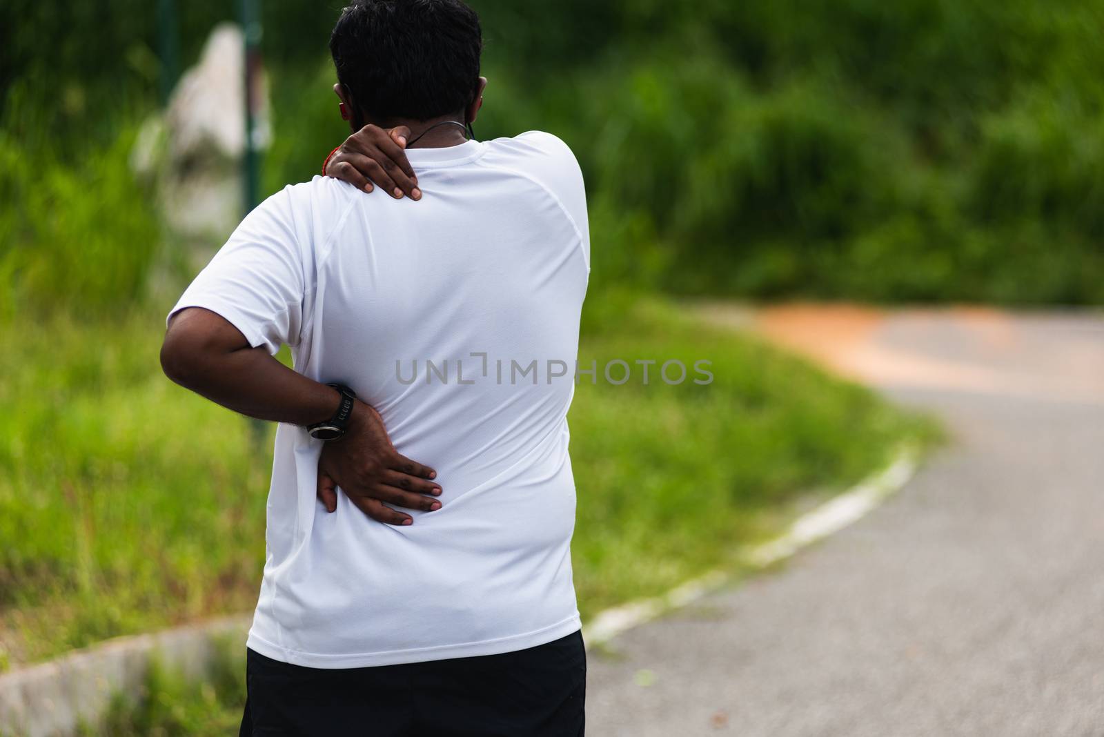 Close up Asian young sport runner black man wear watch hands joint hold back and shoulder he is pain while running at the outdoor street health park, healthy exercise Injury from workout concept