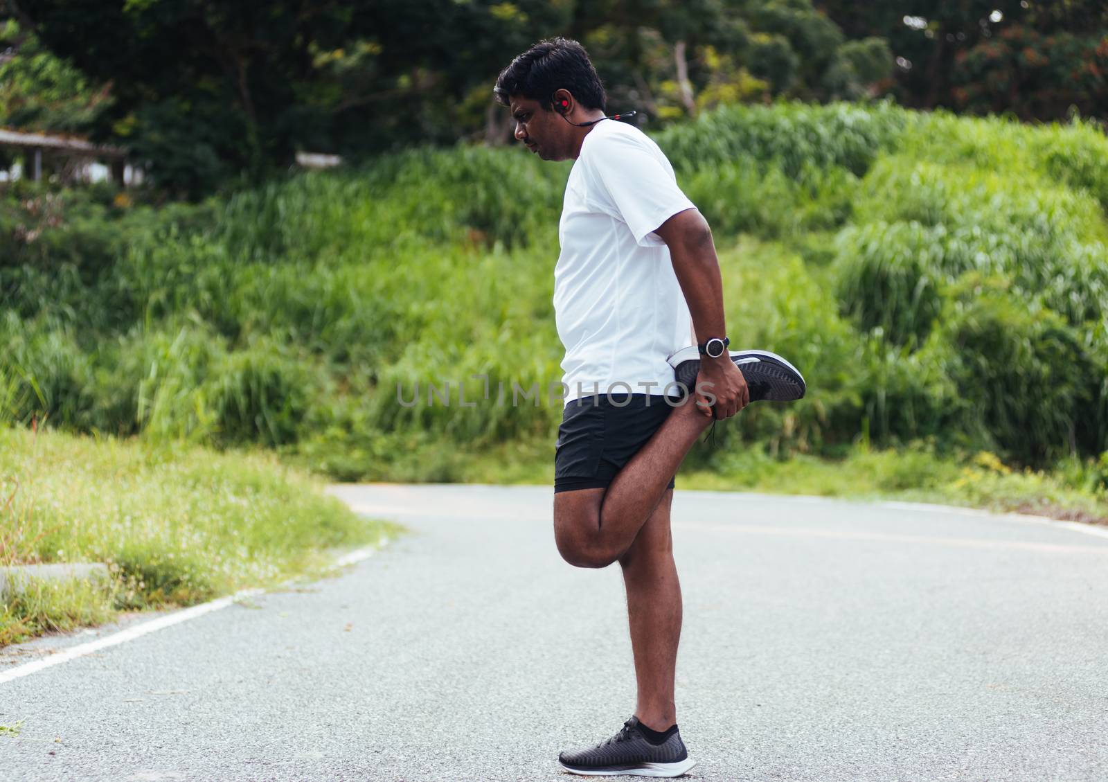 Close up Asian young athlete sport runner black man wear watch lift feet stretching legs and knee before running at the outdoor street health park, healthy exercise before workout concept