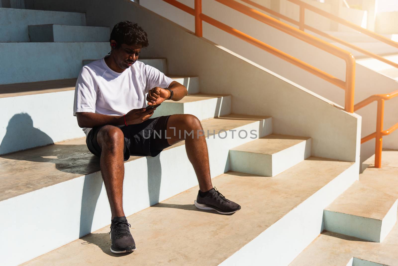 Close up Asian young athlete sport runner black man wear modern time smart watch and sync to a smartphone check running result after a training run at the outdoor, healthy exercise workout technology