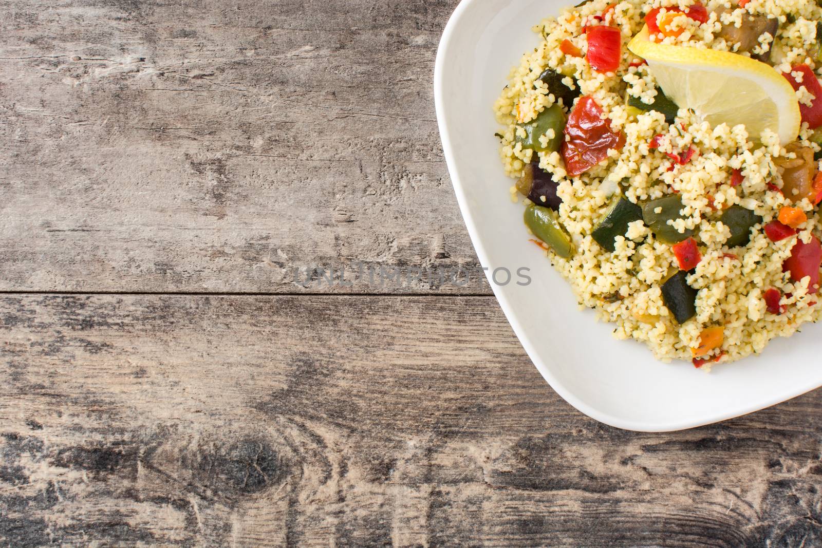 Couscous with vegetables on wooden table