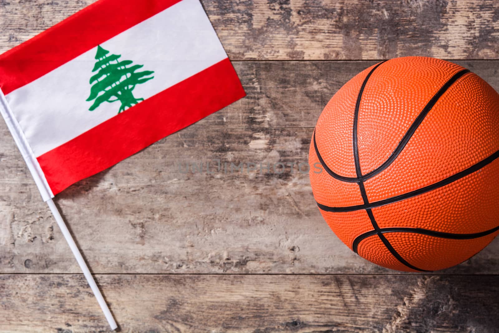 Lebanese flag and basketball on wooden table. Top view