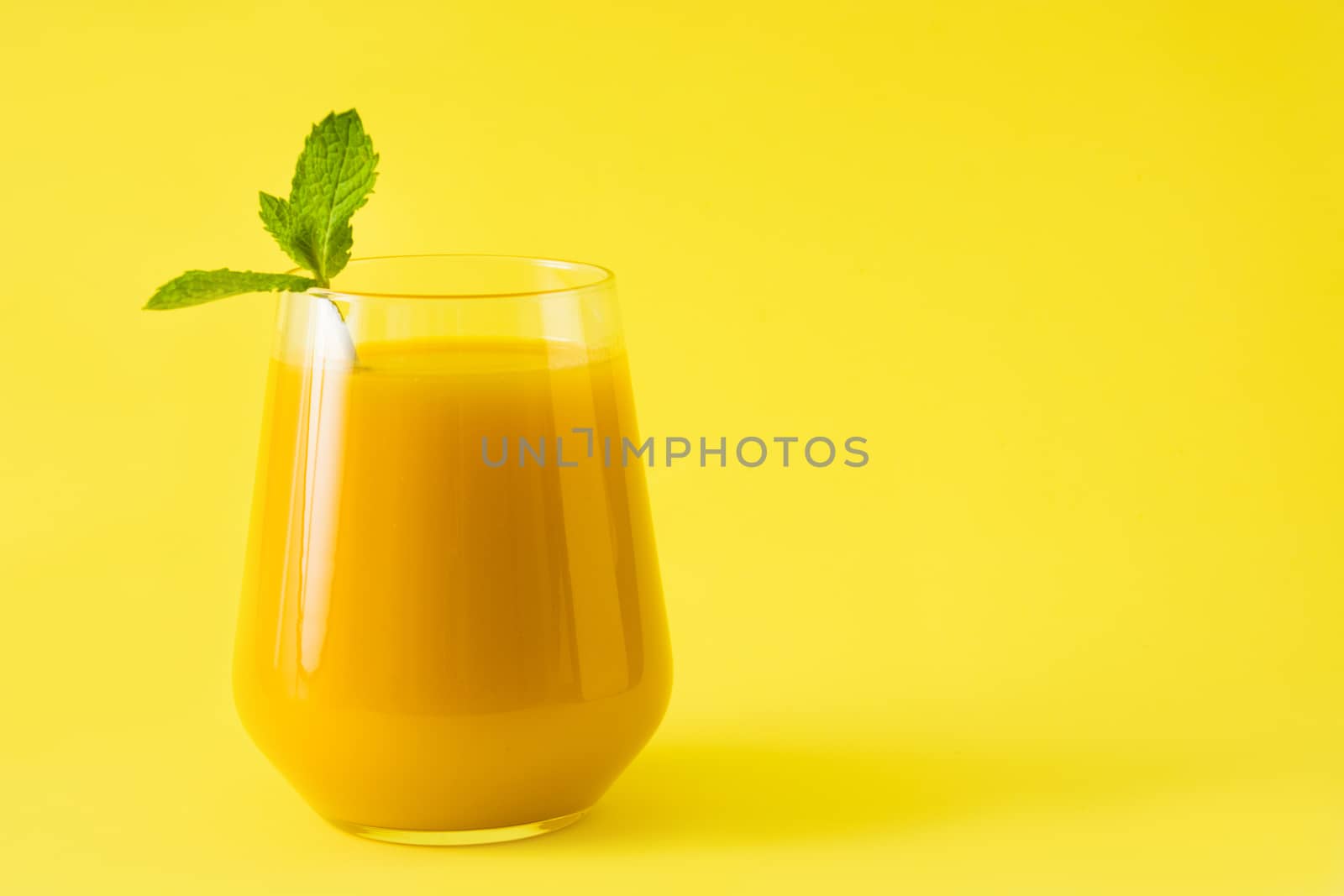 Mango Lassi dessert. Traditional Indian drink on yellow background.