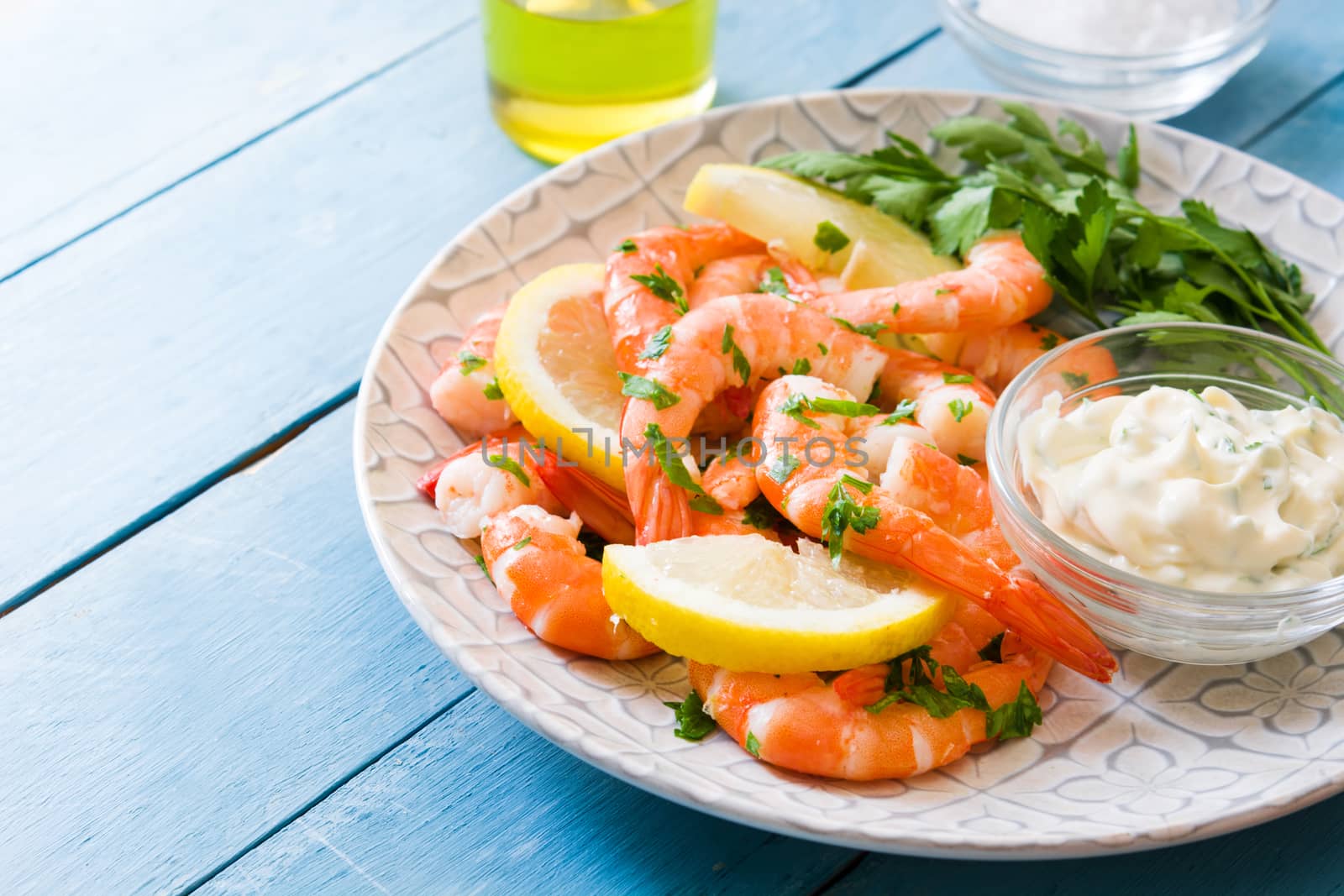 Grilled shrimps, parsley and lemon on blue wooden table