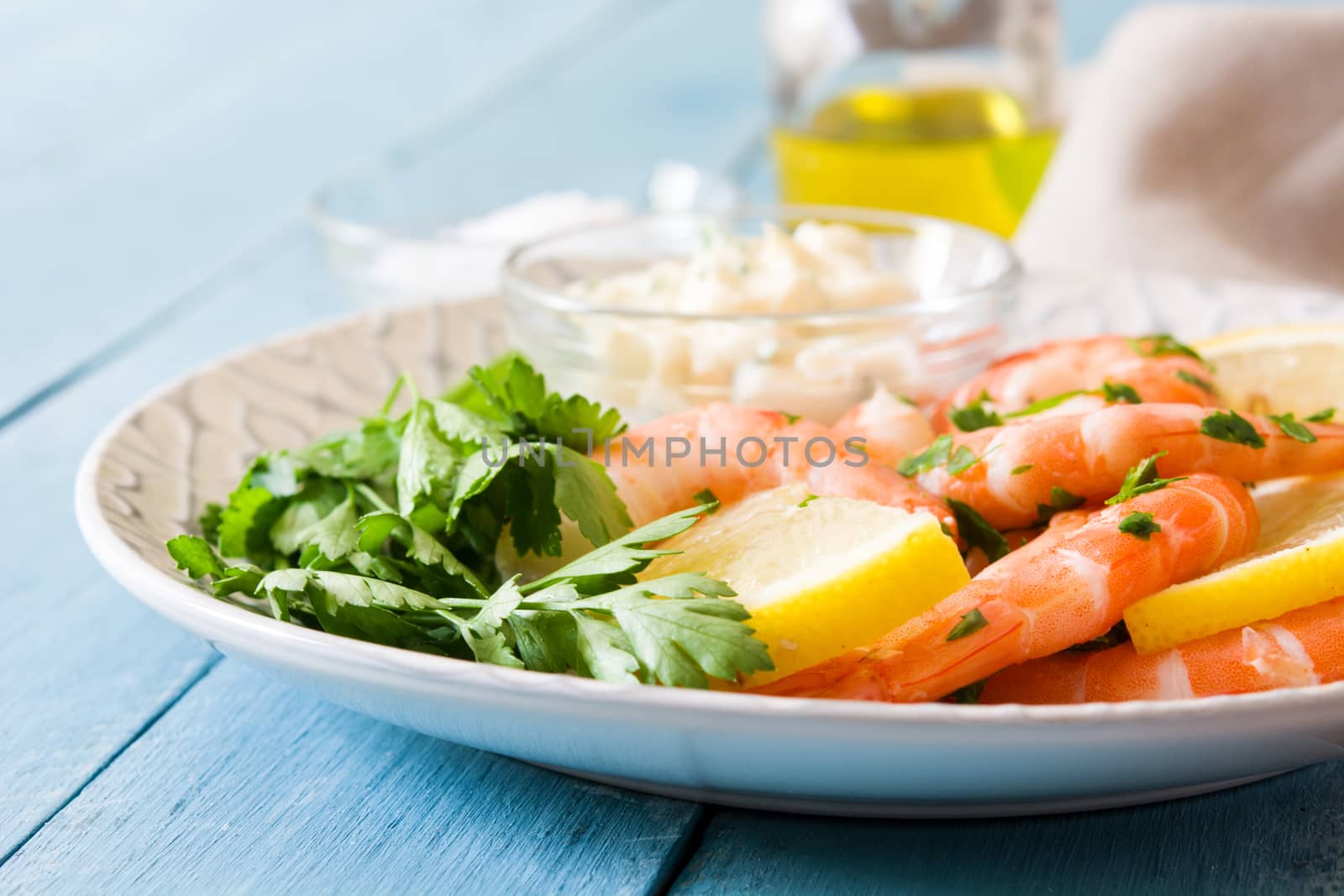 Grilled shrimps, parsley and lemon on blue wooden table by chandlervid85