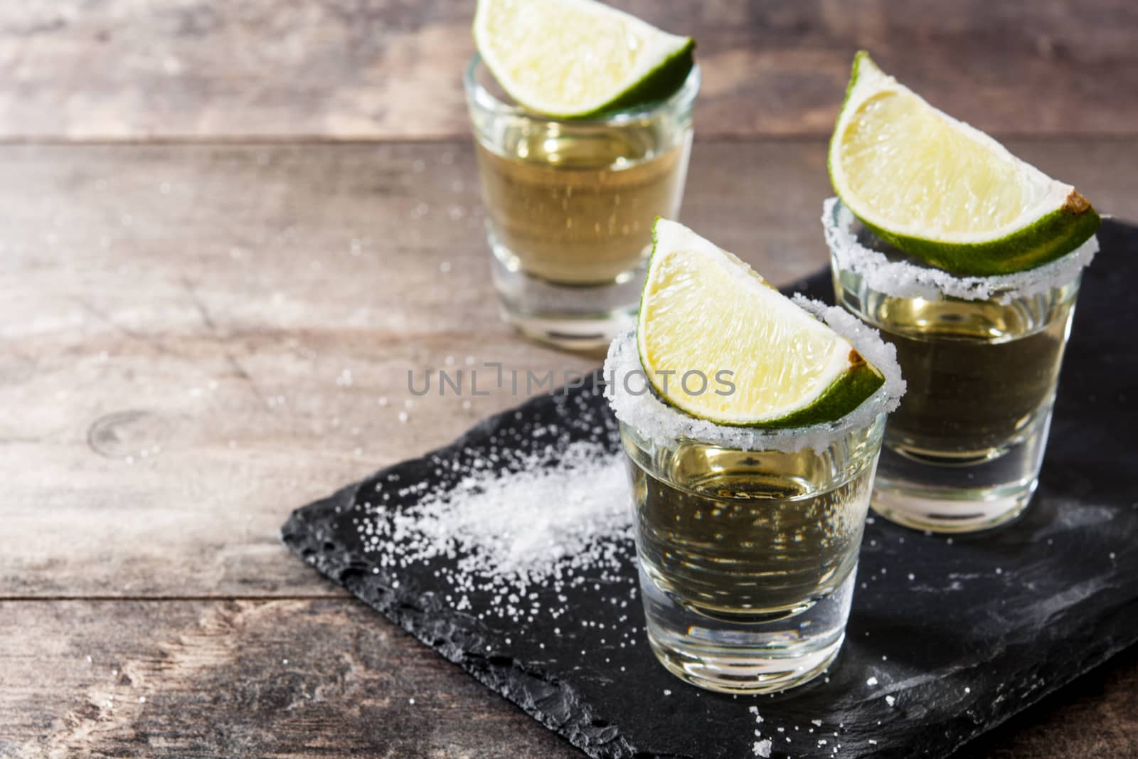 Mexican Gold tequila with lime and salt on wooden table. by chandlervid85