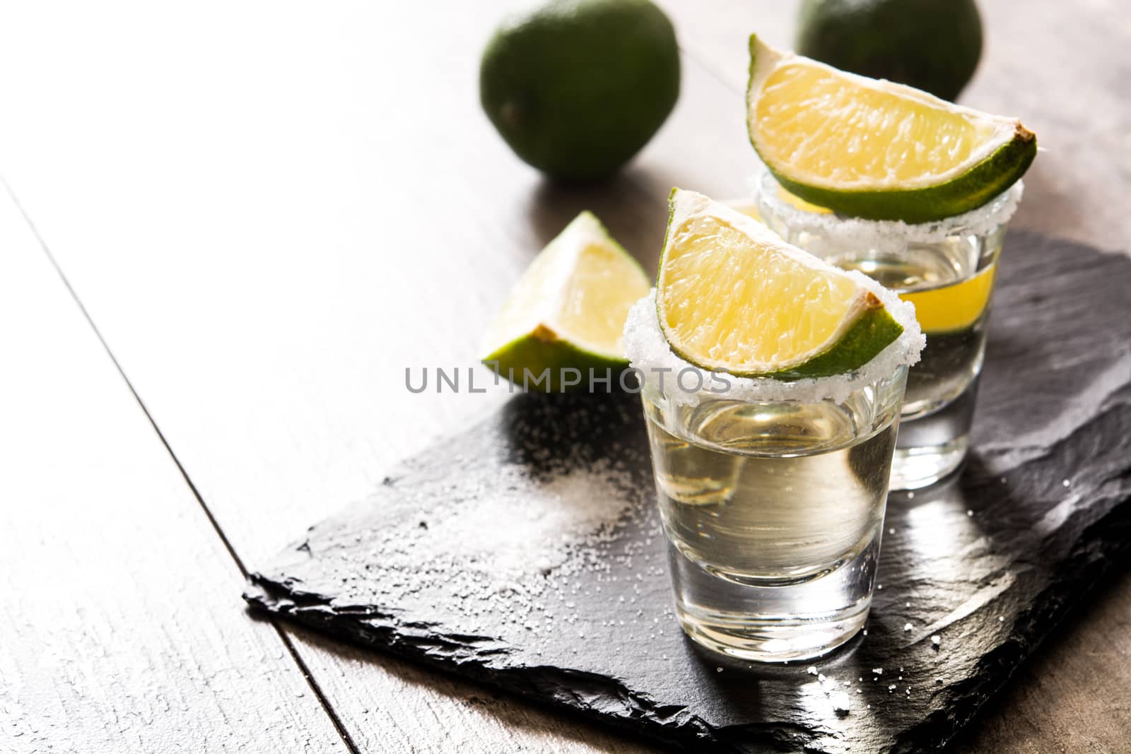 Mexican Gold tequila with lime and salt on wooden table.