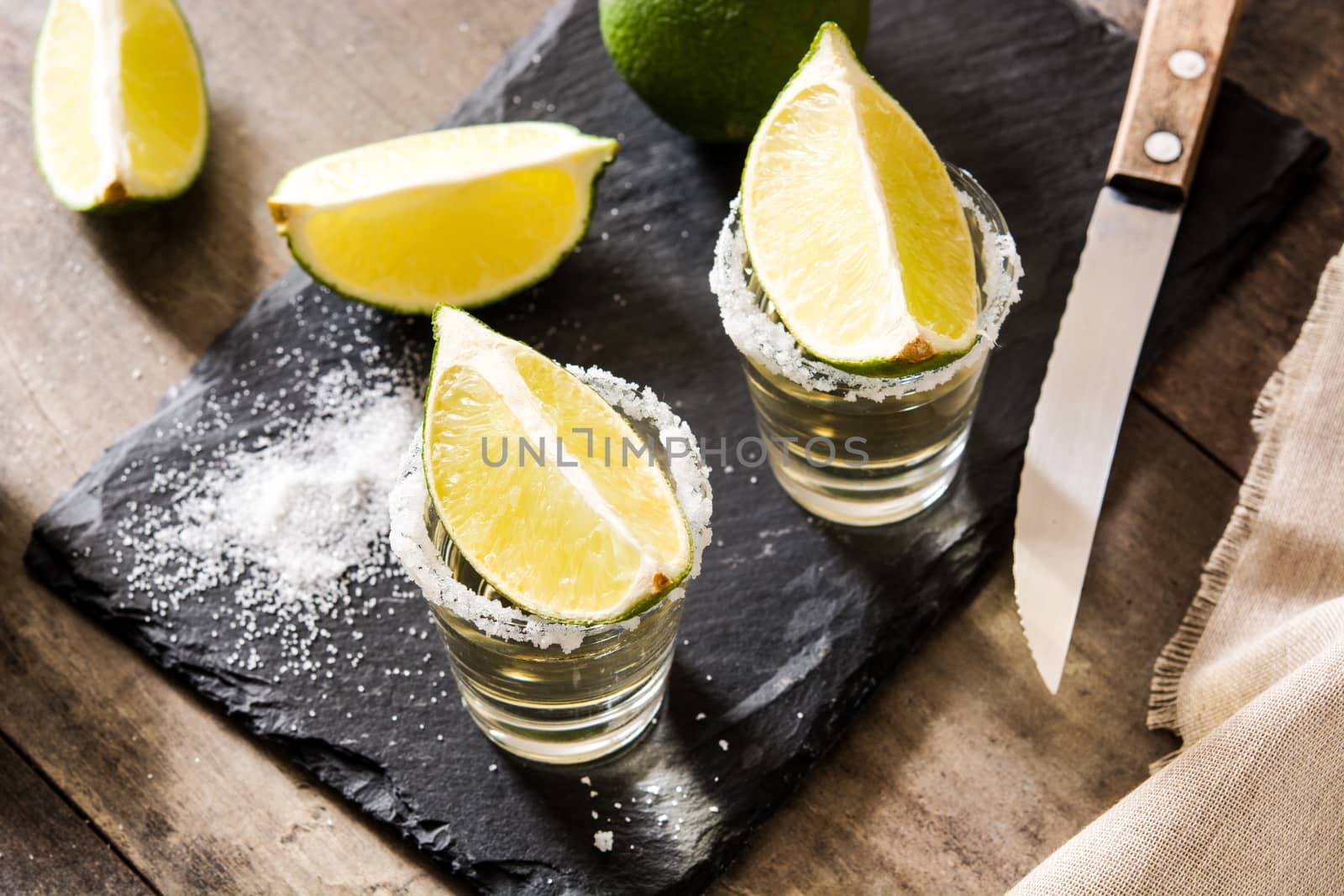 Mexican Gold tequila with lime and salt on wooden table.