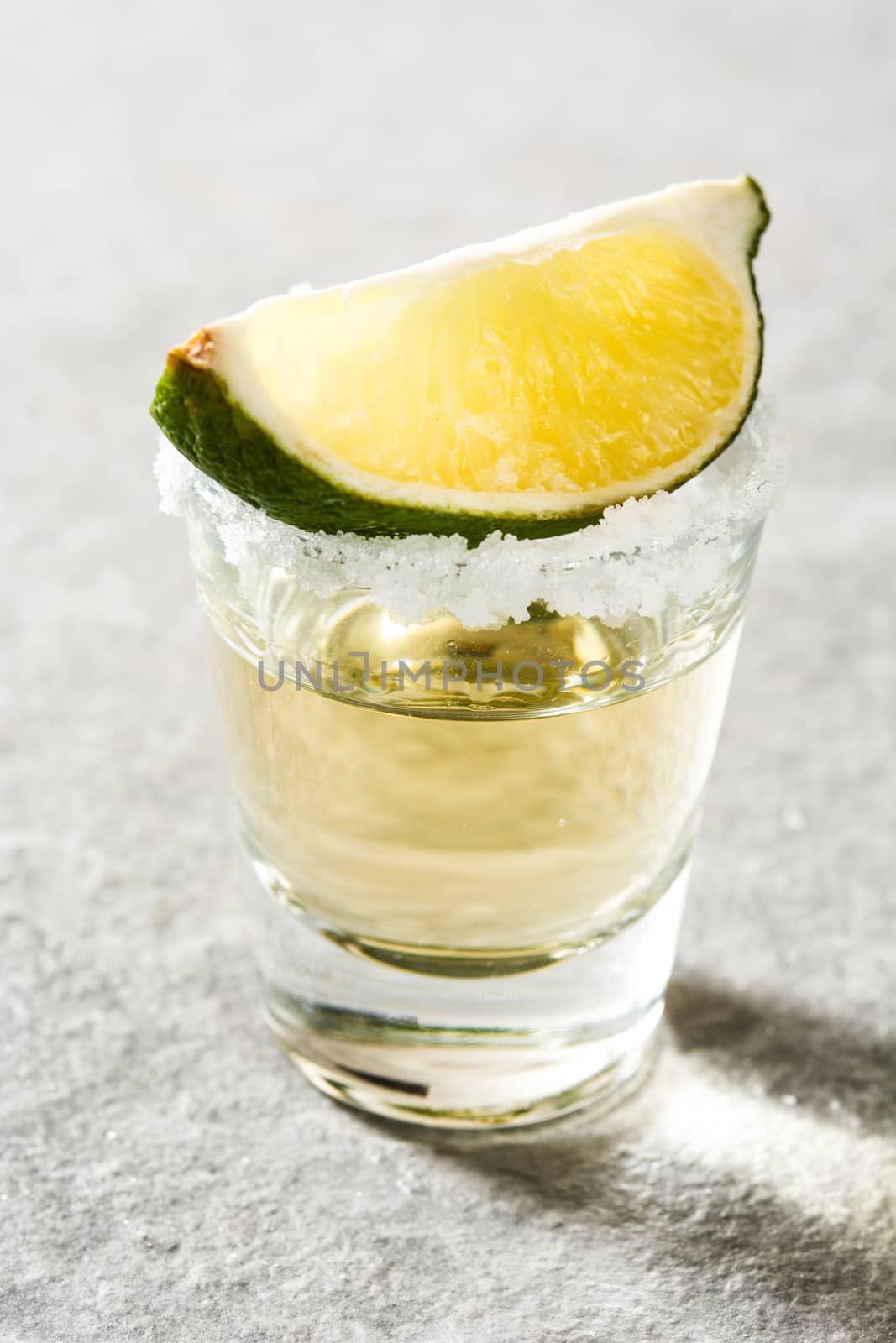Mexican Gold tequila with lime and salt on gray background by chandlervid85