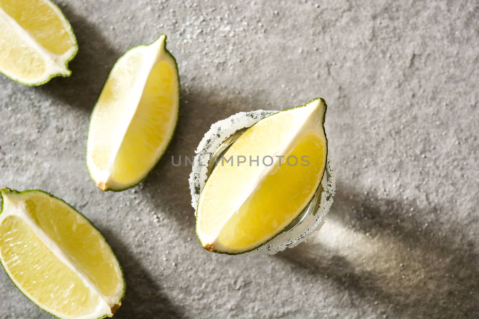 Mexican Gold tequila with lime and salt on gray background by chandlervid85