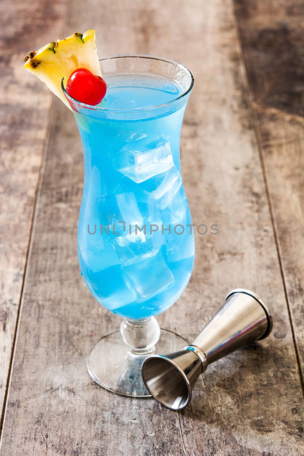Blue Hawaiian cocktail on wooden table by chandlervid85