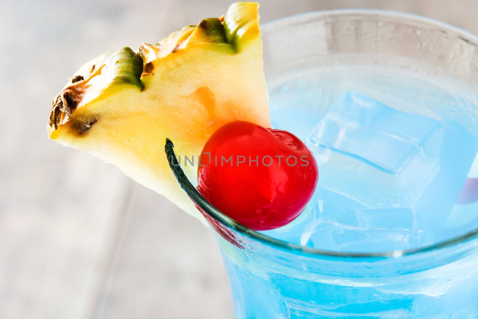Blue Hawaiian cocktail on wooden table by chandlervid85