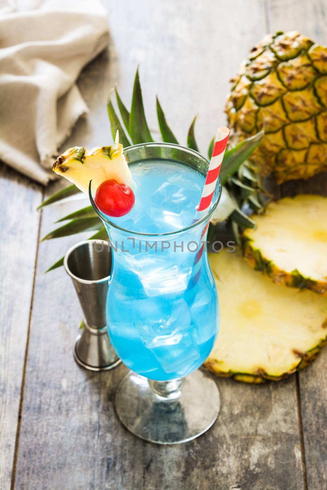 Blue Hawaiian cocktail on wooden table by chandlervid85