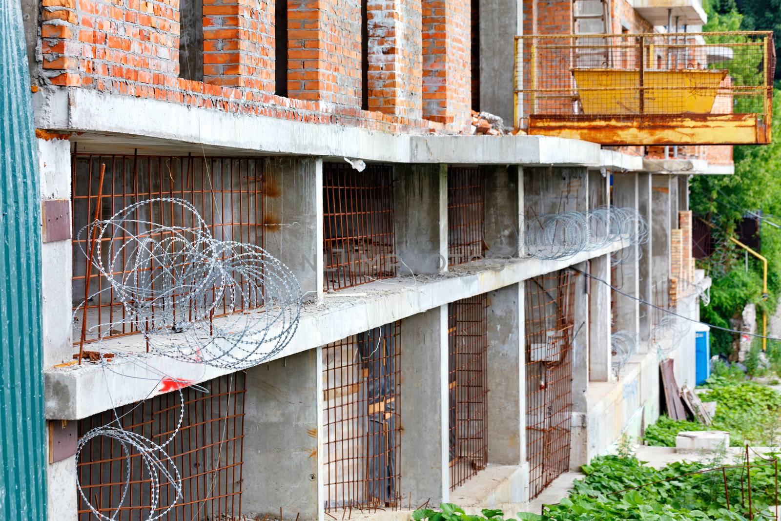 Barbed wire and rusty iron rods prevent entry into an abandoned construction site in the industrial zone.
