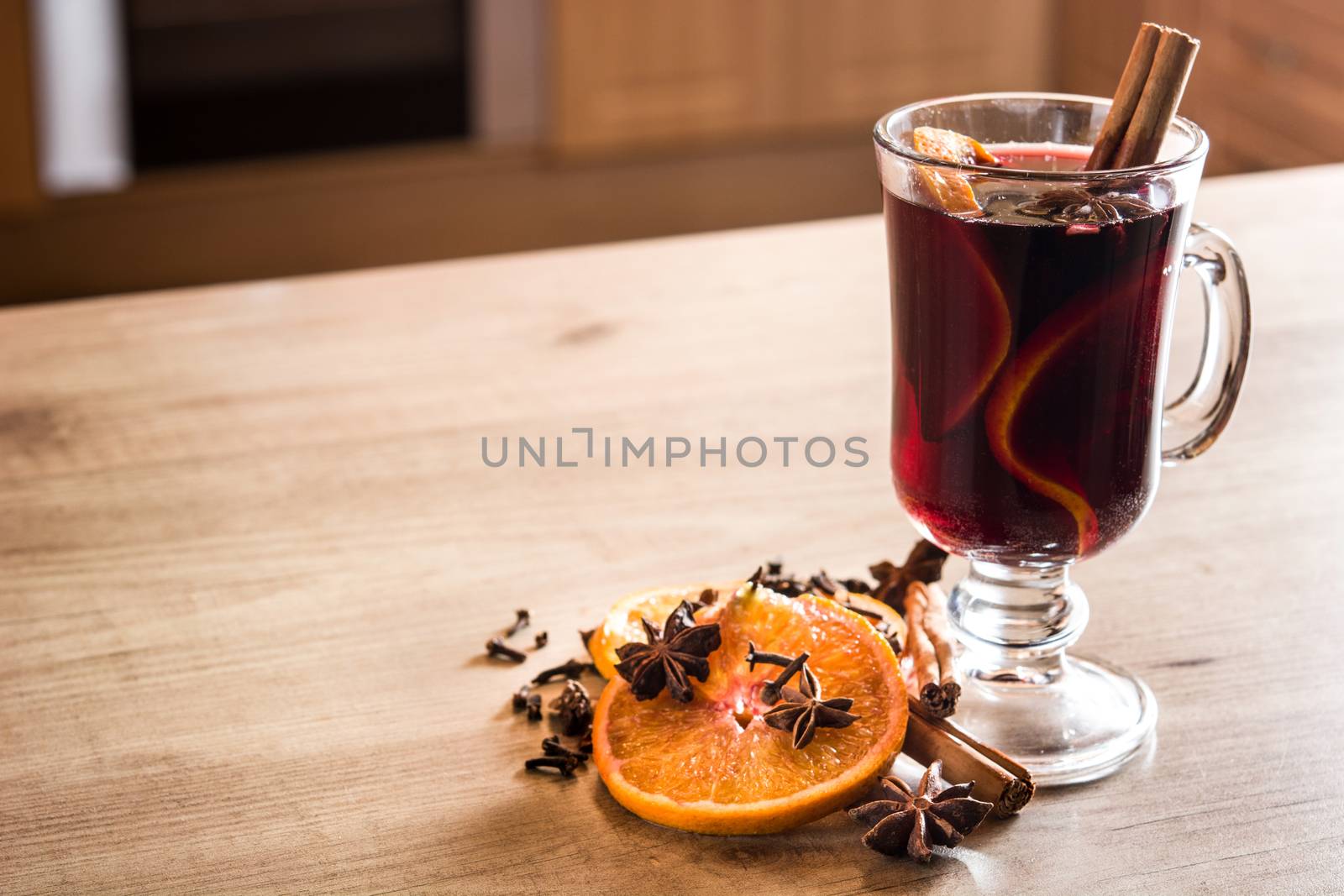 Mulled wine in glass with spice and fruit on wooden table. Copyspace