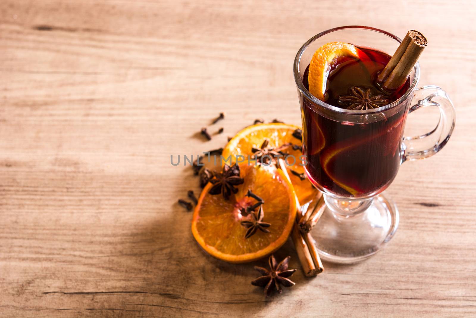 Mulled wine in glass with spice and fruit on wooden table. by chandlervid85