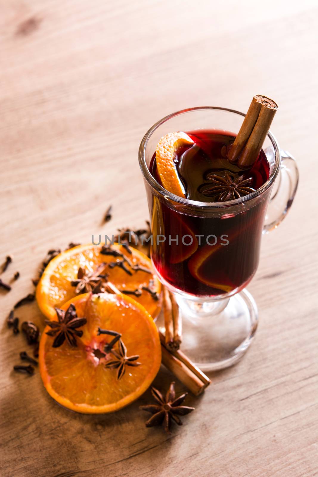 Mulled wine in glass with spice and fruit on wooden table. by chandlervid85