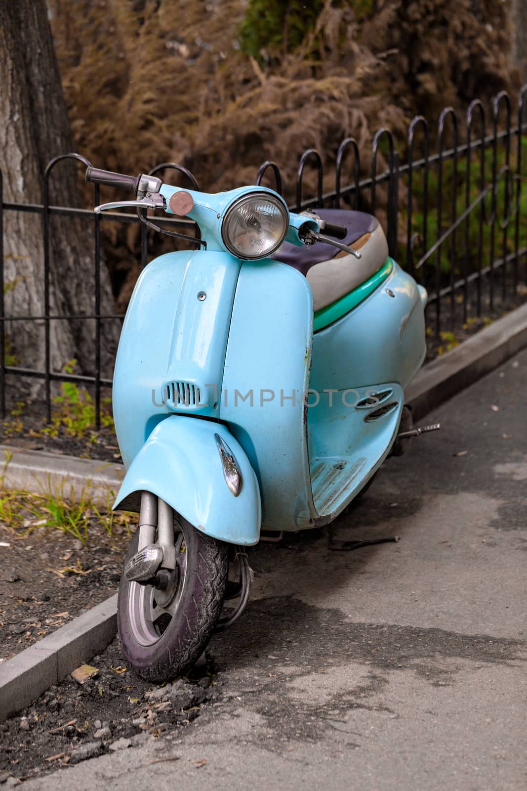 Light blue retro scooter parked on the old street of the city. Vintage style. Copy space.
