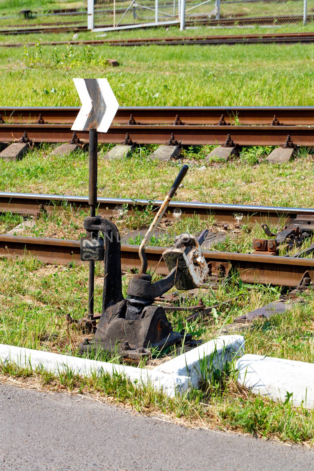 Vintage manual translator of railway arrows. The mechanism of the railway switch on the background of railway tracks and green grass on a sunny day.