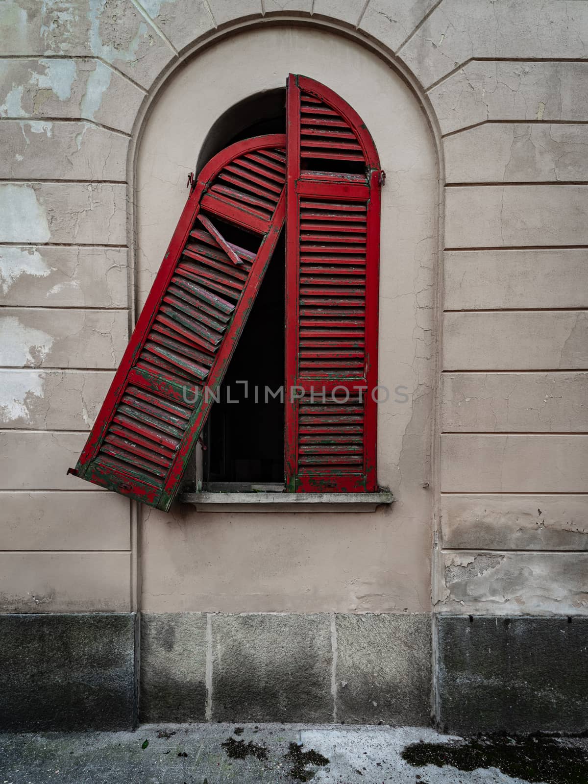 Red doors of a window of an old dilapidated Italian building of the twentieth century, urbex image