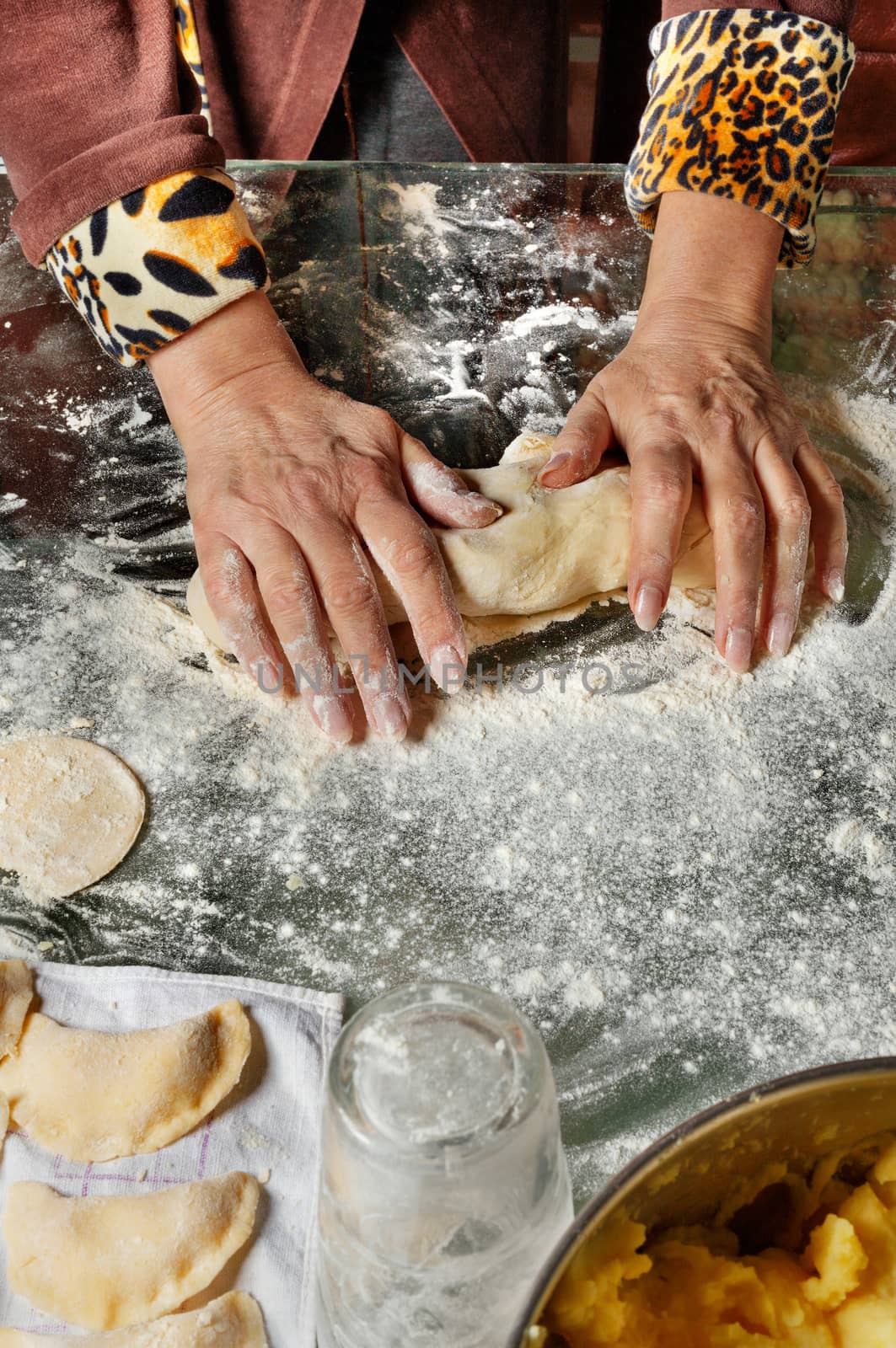 A housewife kneads dough with her hands for making vareniki with potatoes in Ukrainian national cuisine. by Sergii