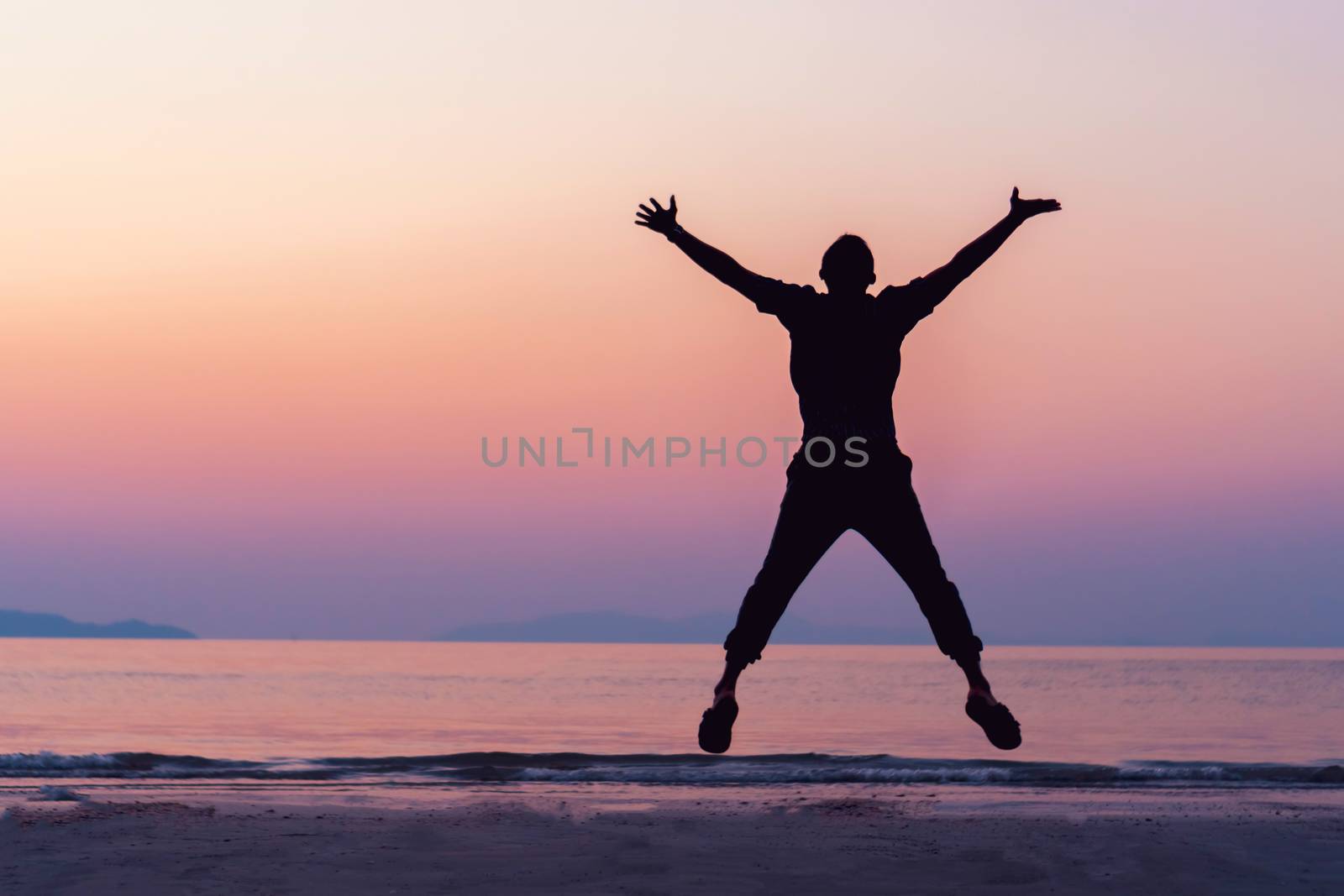 Silhouette man rise hands up and jump to sky freedom concept with sunset sky and summer beach season. by Suwant