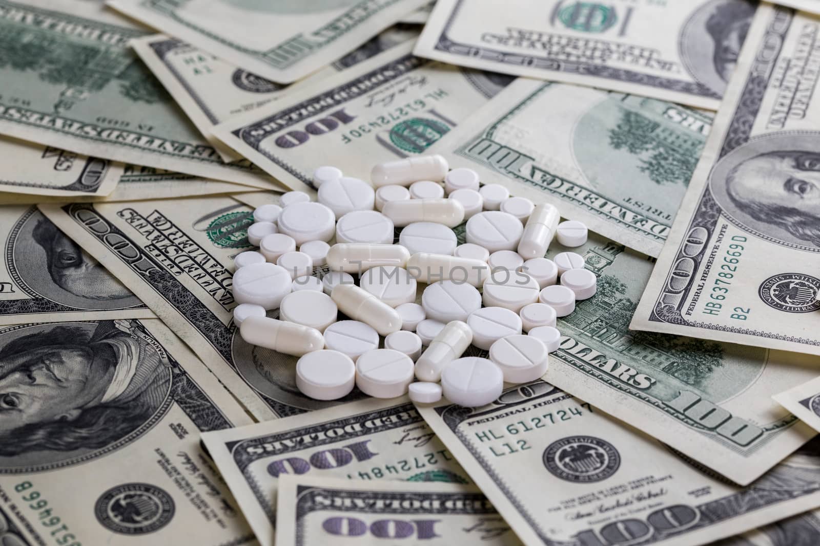 handful of white pills on dollar bills close-up with selective focus