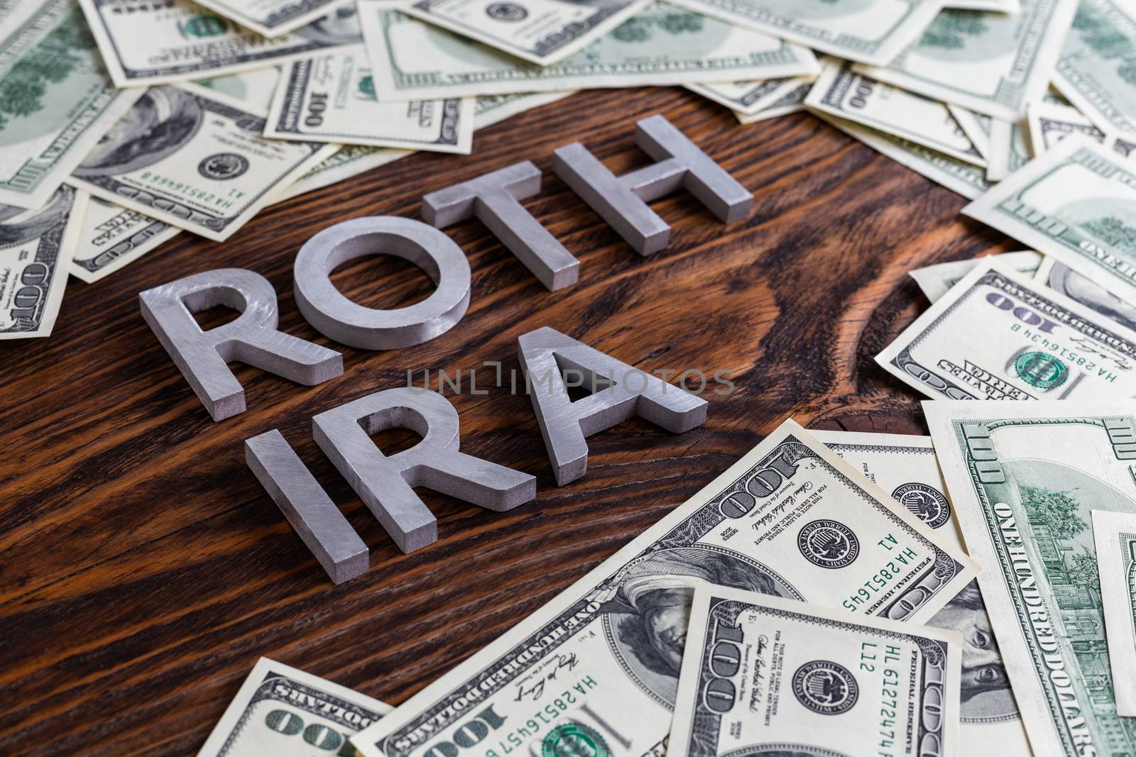 words ROTH IRA laid on wooden surface with metal letters us paper currency