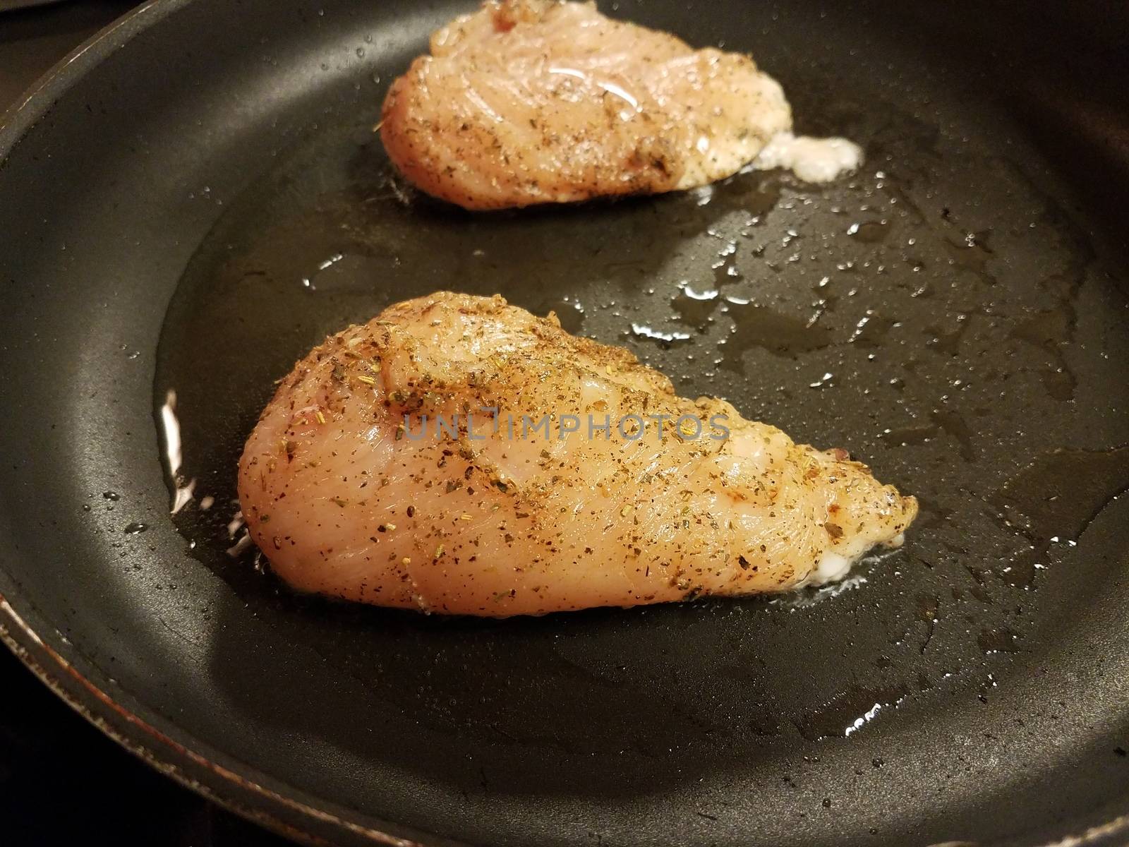 seasoned chicken breast or poultry in pan or skillet with oil
