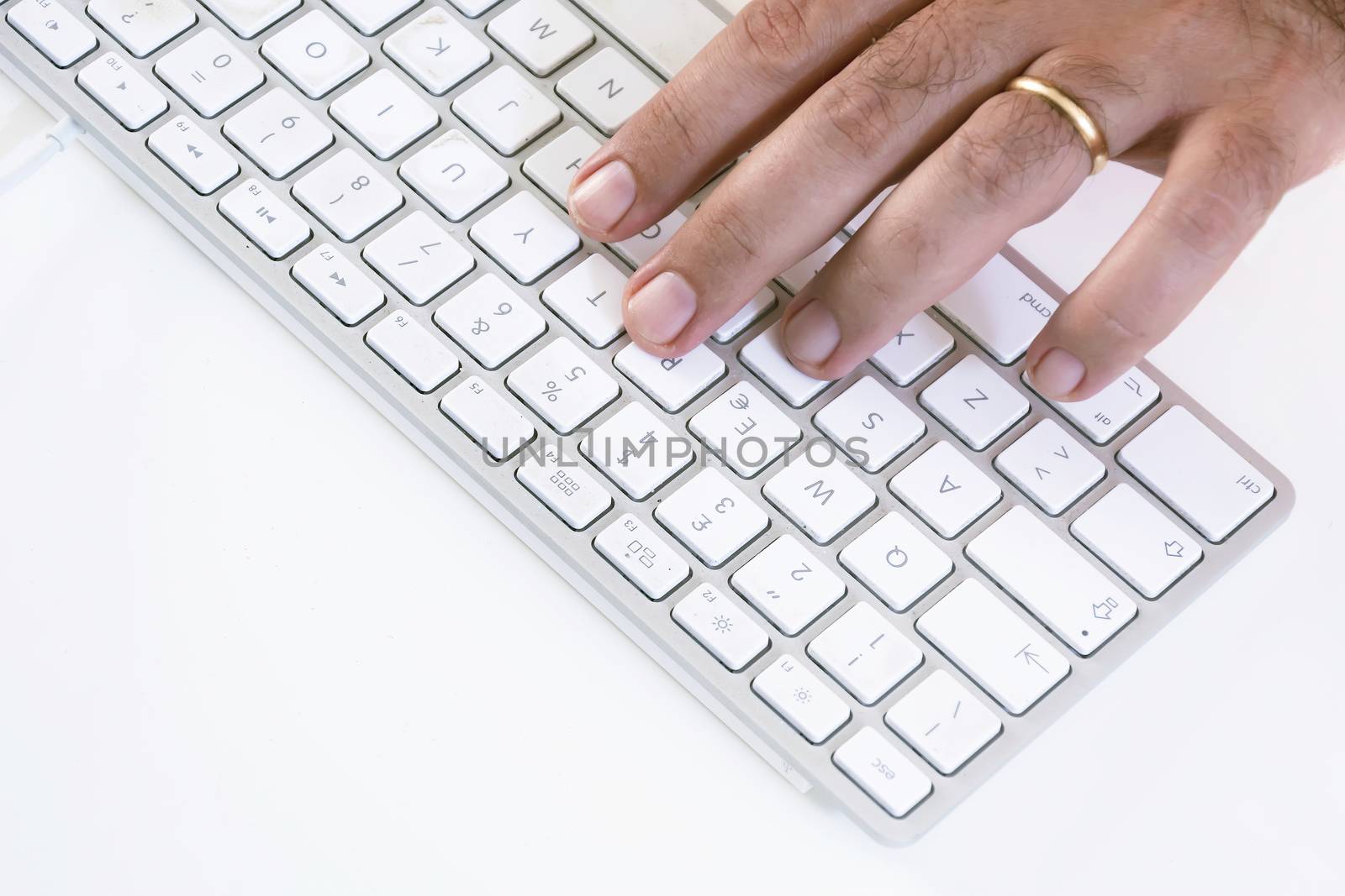 male hand typing on a white keyboard on a white table. White background.